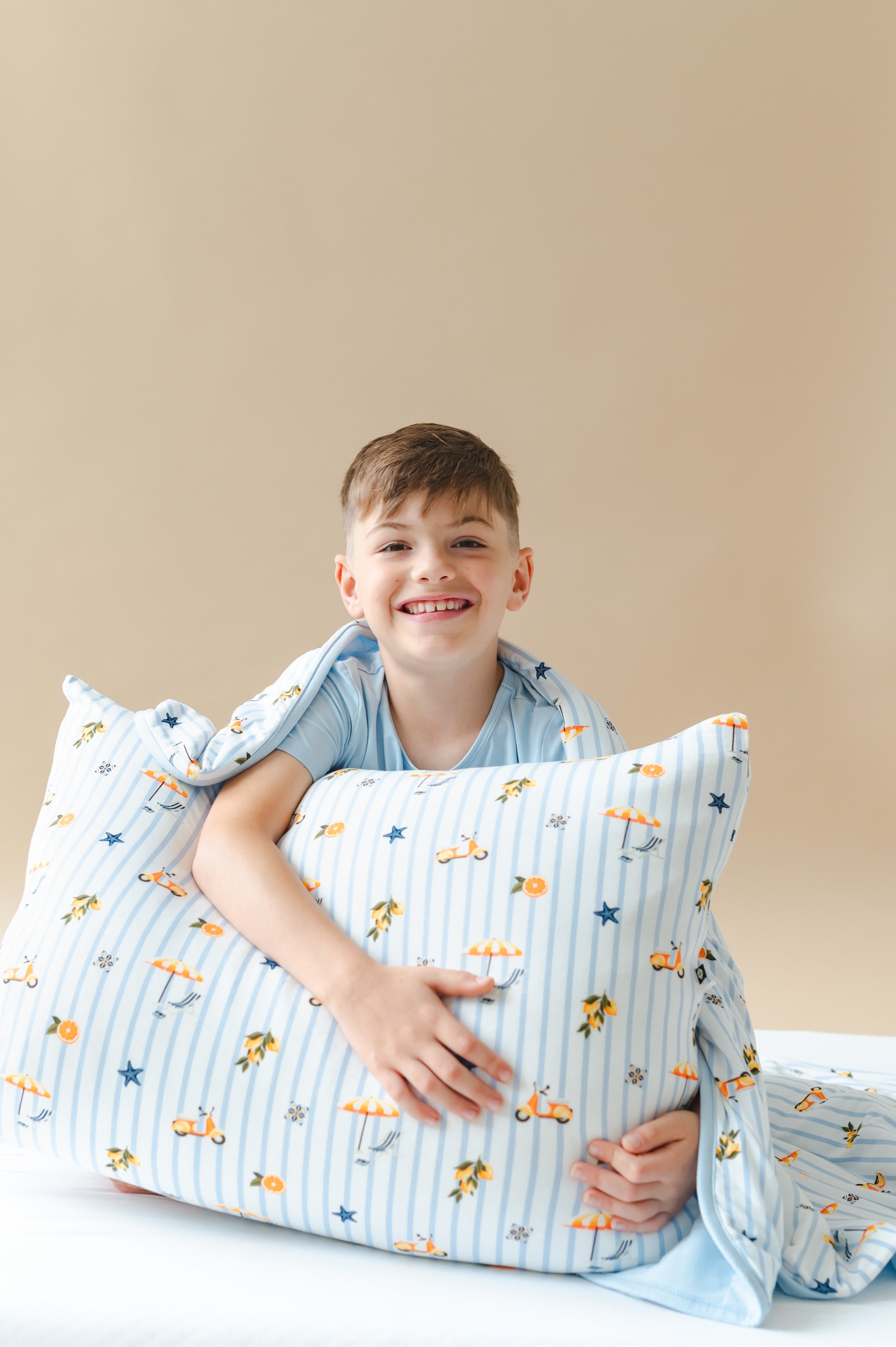 Young boy sitting on the bed holding a Standard Pillowcase in Amalfi Coast