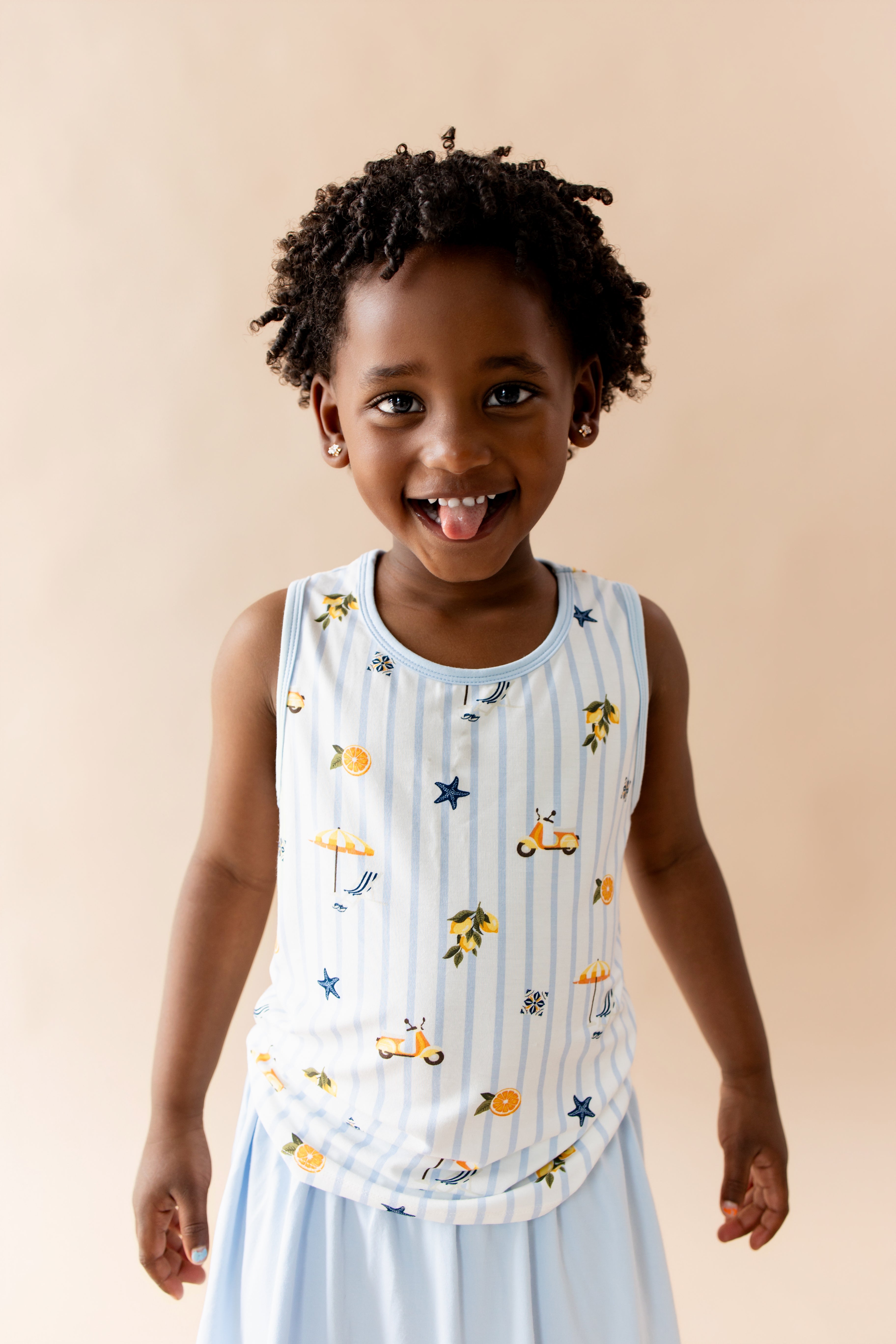 Close up of young girl wearing the Toddler Tank Top in Amalfi Coast with light blue skort