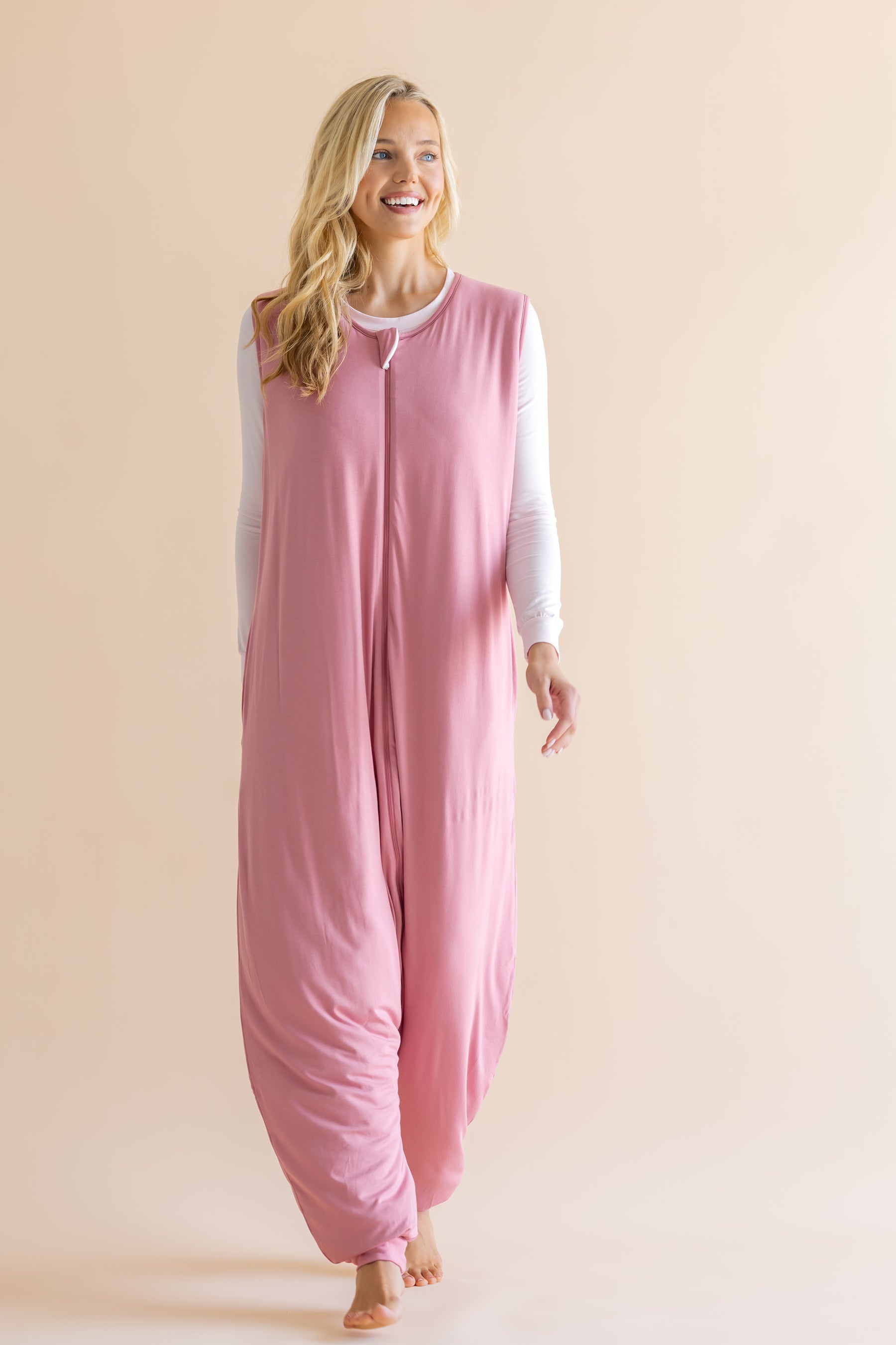 Woman wearing a pink onesie against a beige background