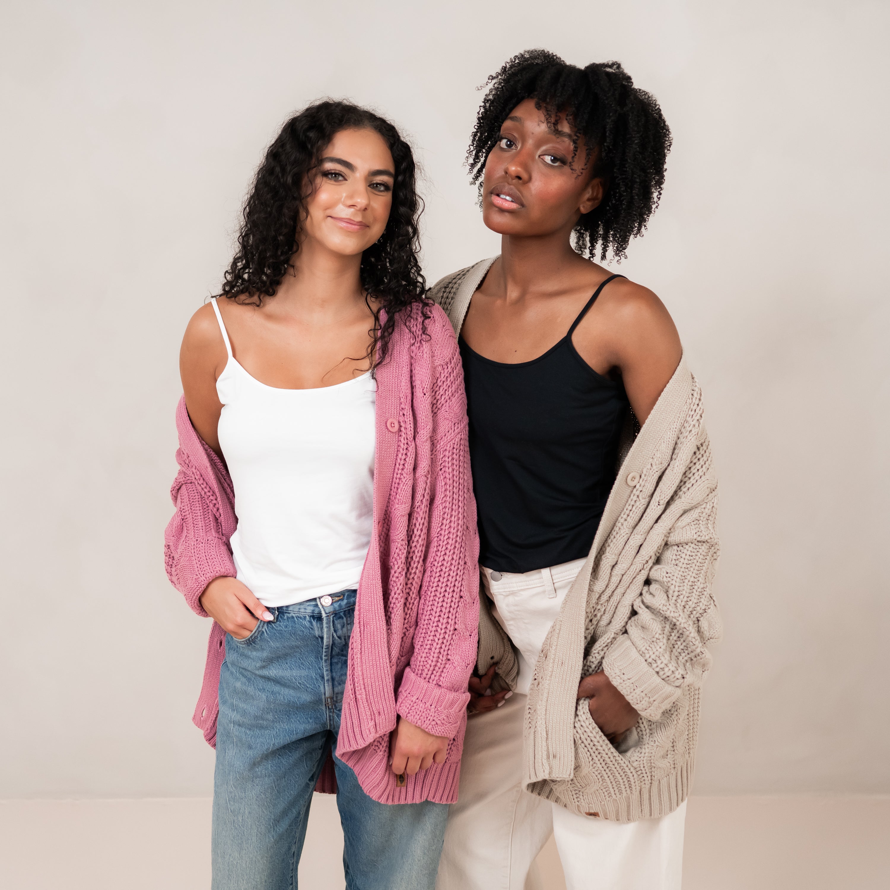 Two female models standing side by side wearing the Cable Knit Adult Cardigan in Almond and Apple Blossom