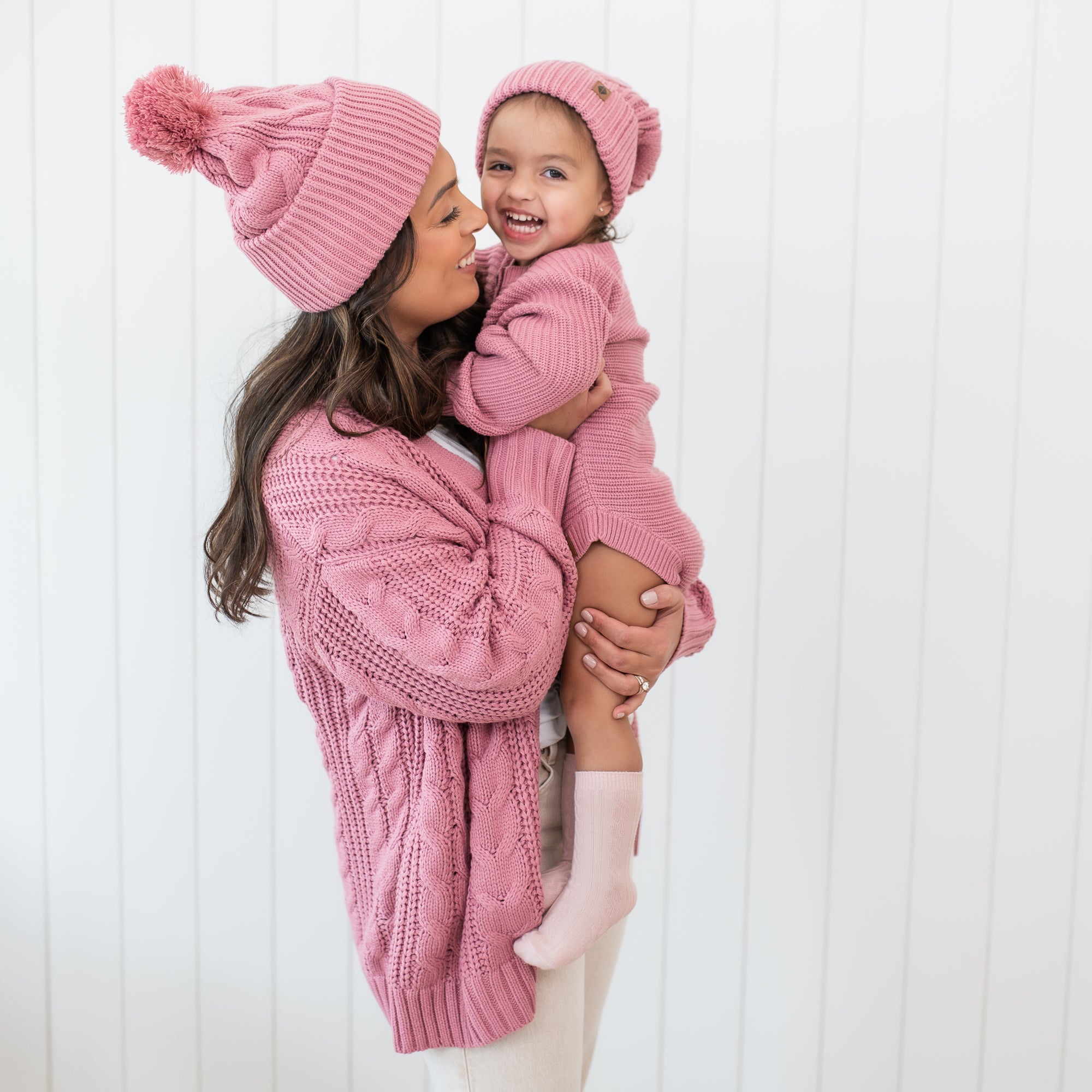 Mother and daughter wearing matching Cable Knit Adult Pom Beanies in Apple Blossom