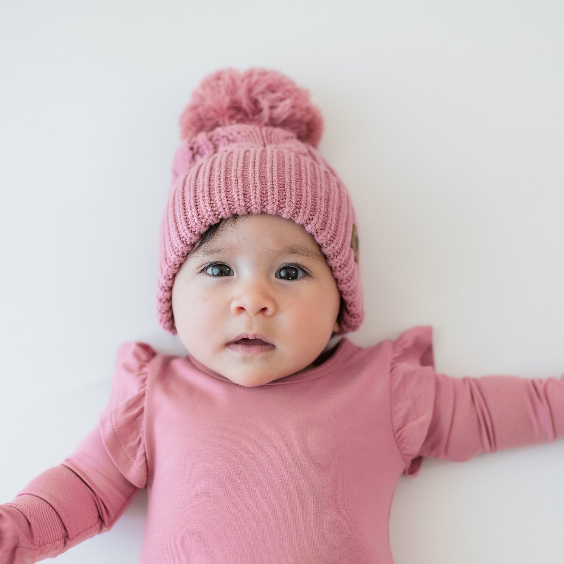 Close up of the Chunky Cable Knit Beanie in Apple Blossom shown on an infant model