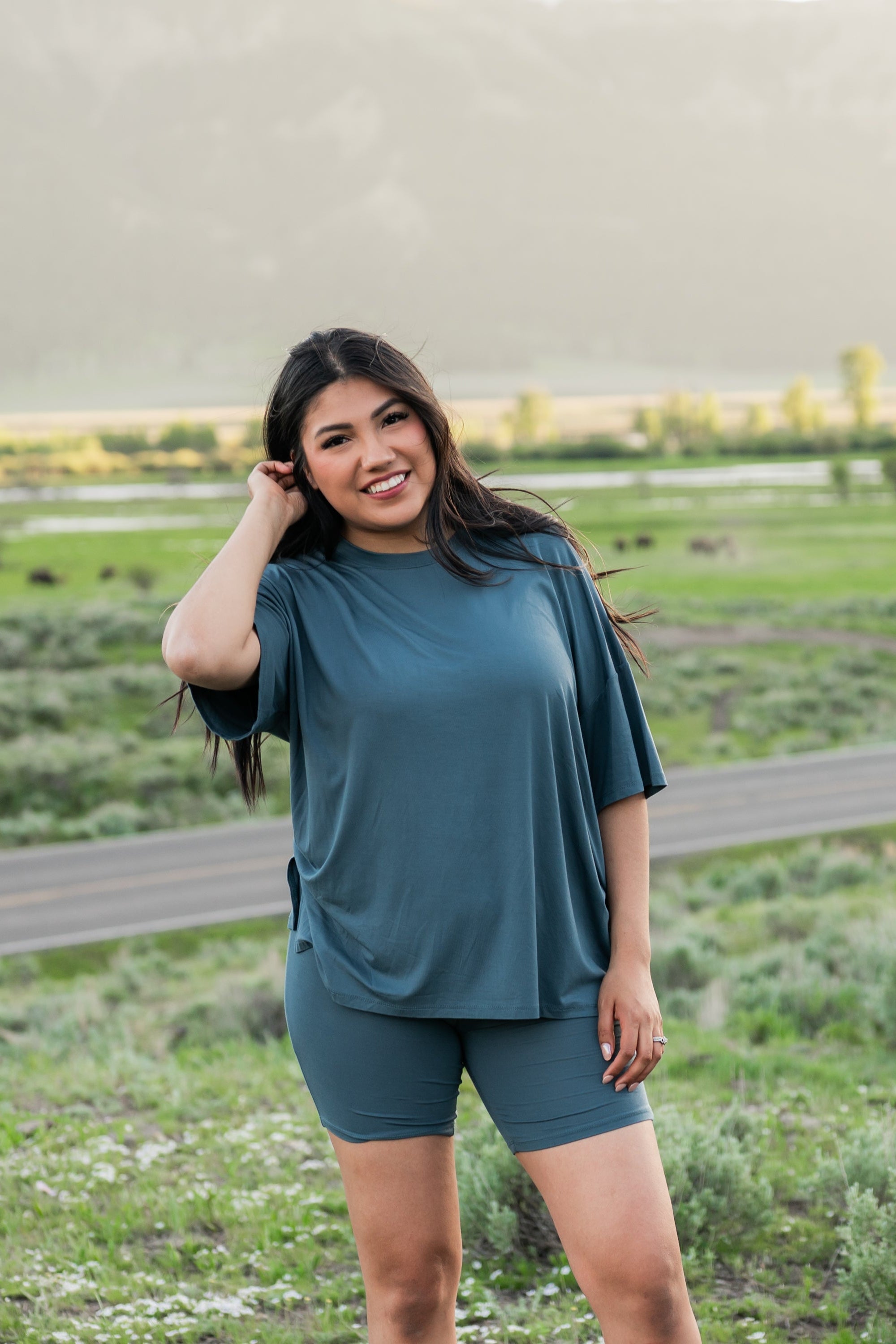 Smiling female model standing in a field wearing the Women’s Biker Short Set in Atlantic