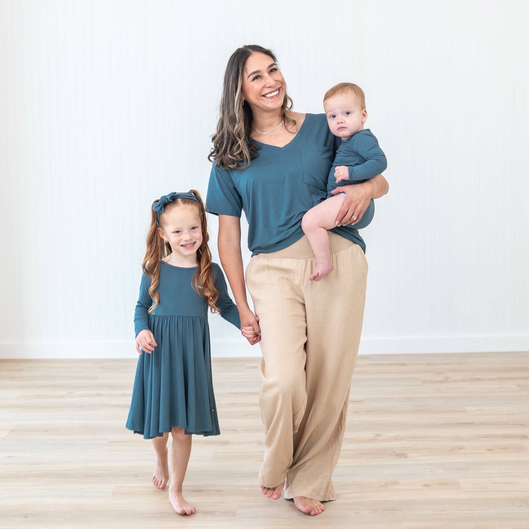 Family matching in Atlantic items. Pictured are the Long Sleeve Twirl Dress in Atlantic, Knotted Bow Headband, Women's V- Neck and Long Sleeve Bodysuit