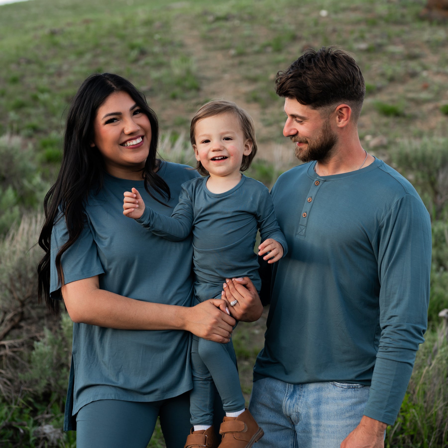 Family matching in Atlantic. Mother wearing Women's Biker Short Set, toddler wearing the Long Sleeve Pajamas in Atlantic and father wearing the Men's Long Sleeve Henley Tee