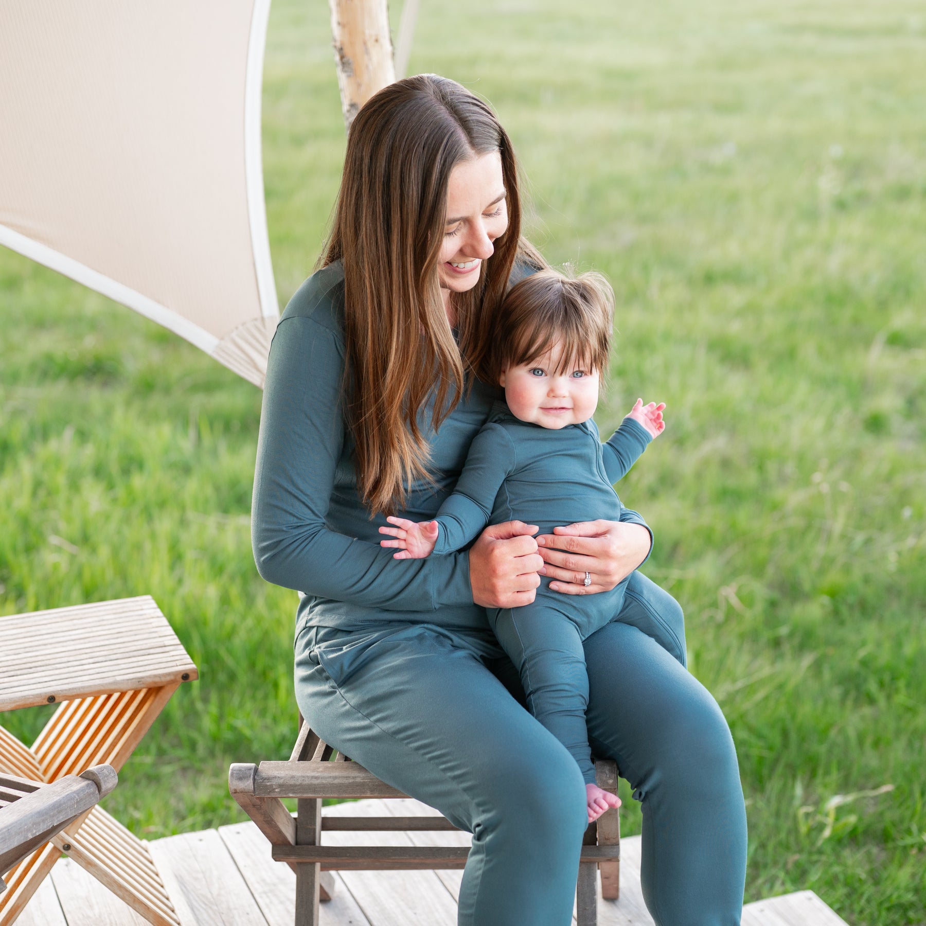 Mother holding infant wearing the Zippered Romper in Atlantic on her lap