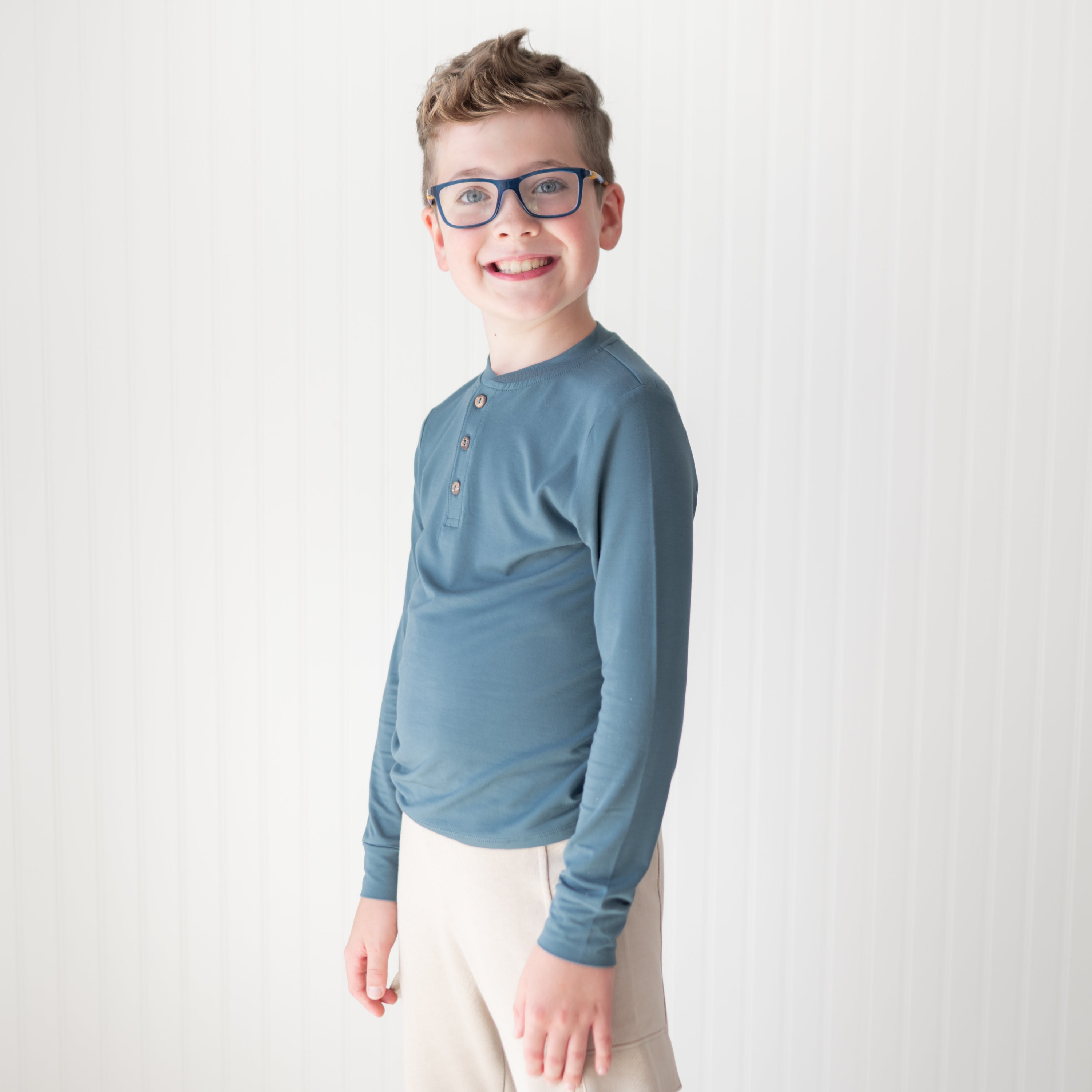 Smiling young boy wearing the Long Sleeve Toddler Henley Tee in Atlantic