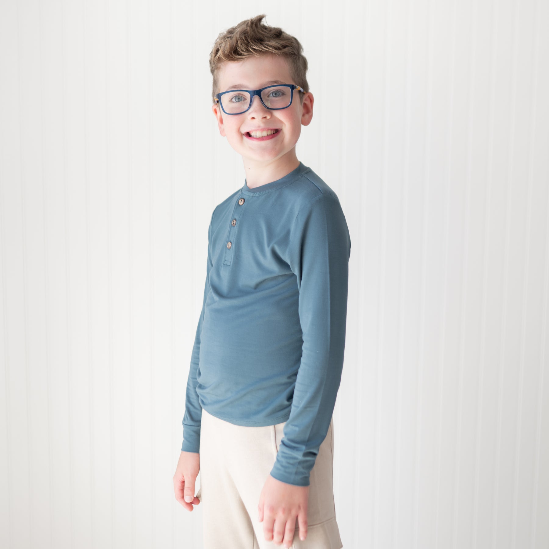 Smiling young boy wearing the Long Sleeve Toddler Henley Tee in Atlantic