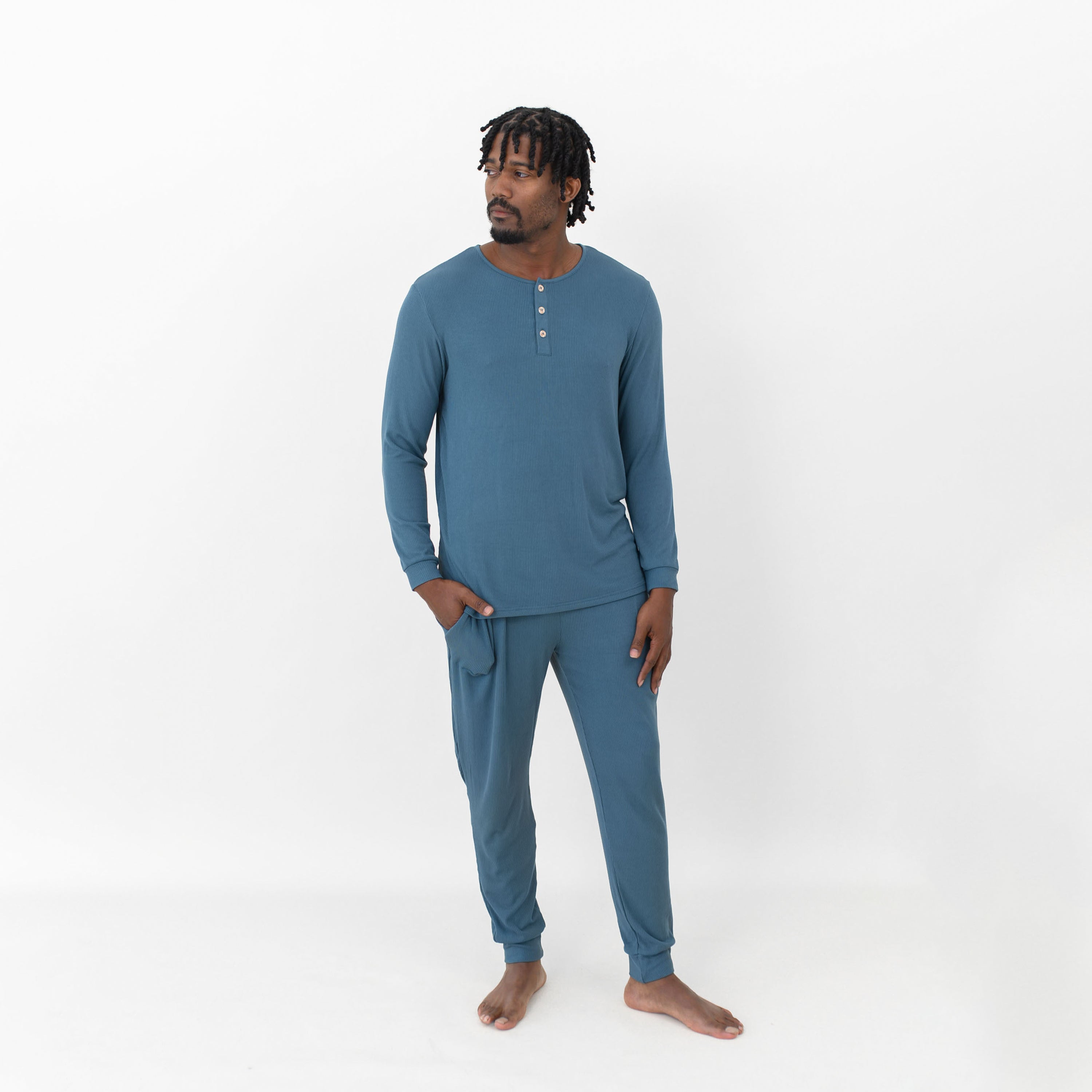 Male model standing looking off to the side with one hand in the pants pocket of the Men's Ribbed Henley Set in Atlantic in front of a white background