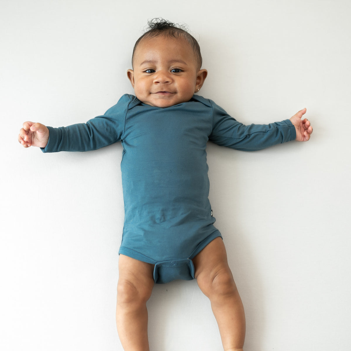 Infant laying down wearing the Long Sleeve Bodysuit in Atlantic