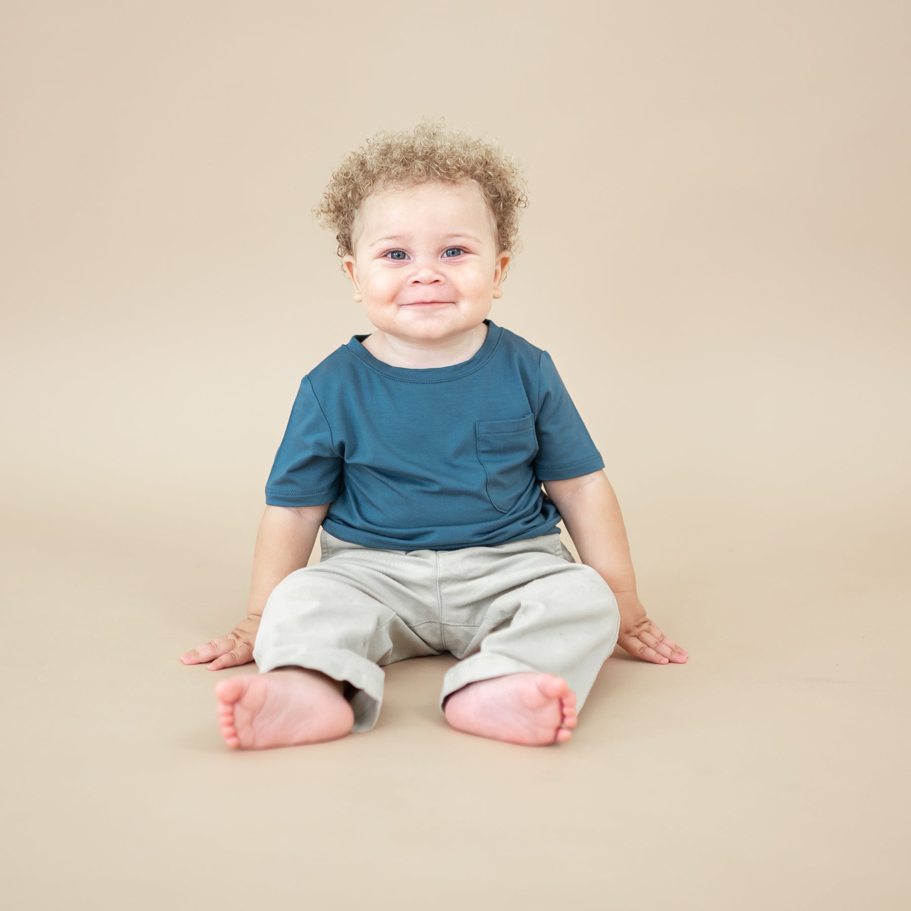 Infant sitting wearing the Toddler Crew Neck Tee in Atlantic with Khaki colored pants