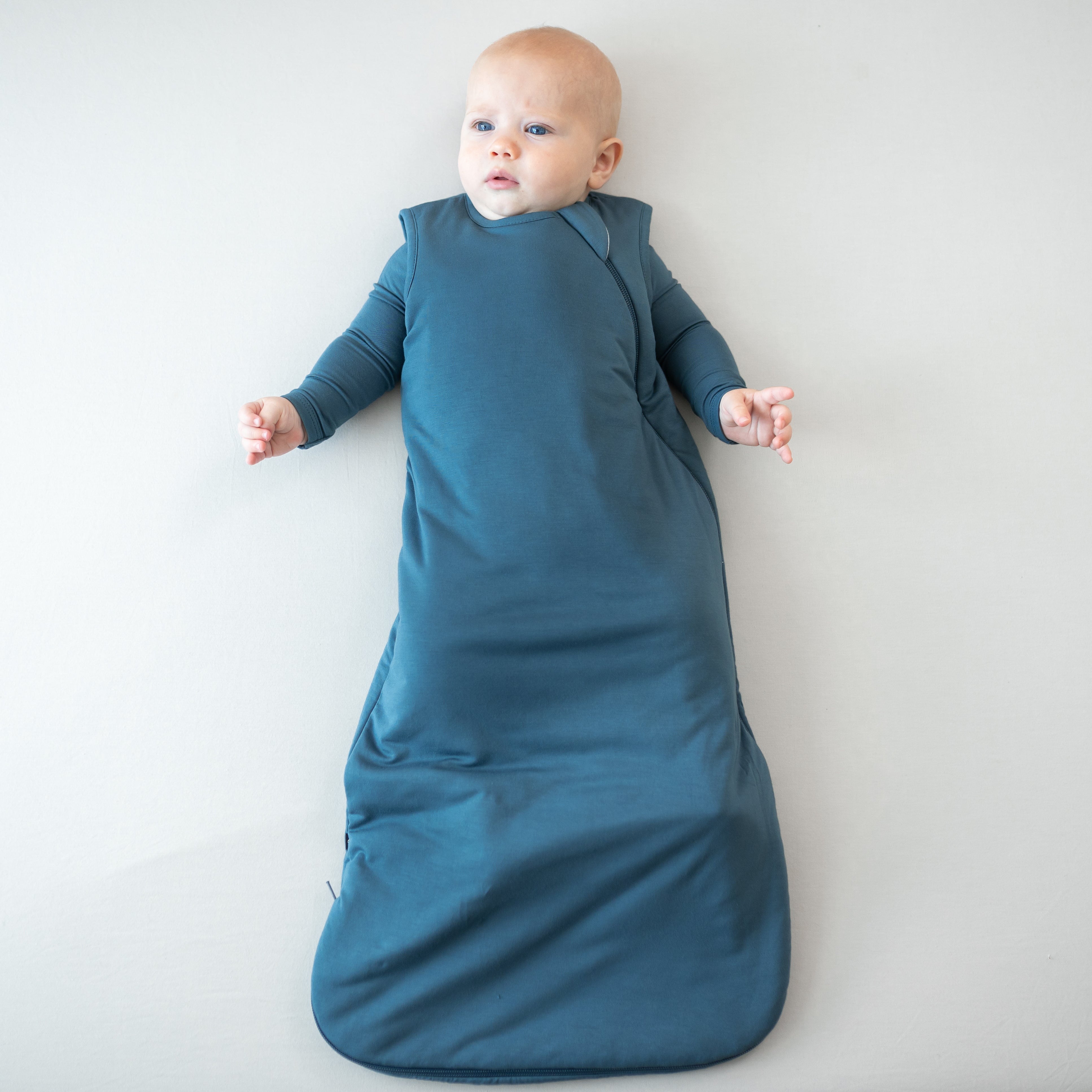 Infant wearing the Sleep Bag in Atlantic 1.0 with matching long sleeve romper underneath