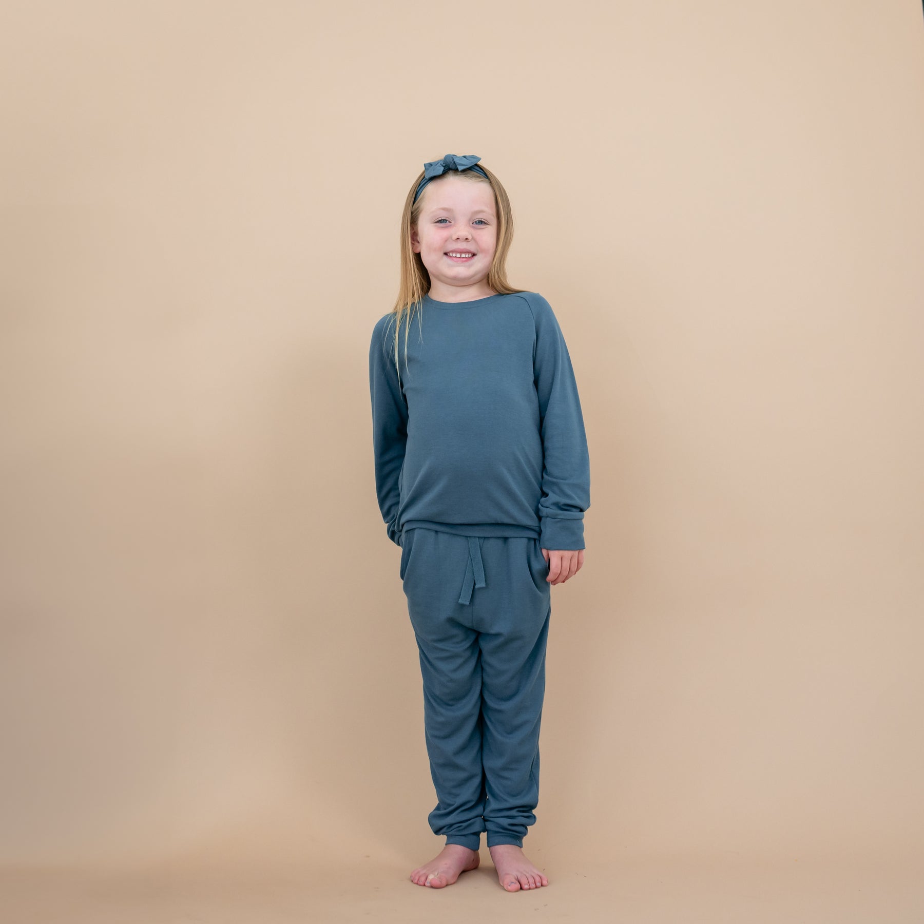 Girl wearing Bamboo Jersey Jogger Set in Atlantic with matching knotted bow headband