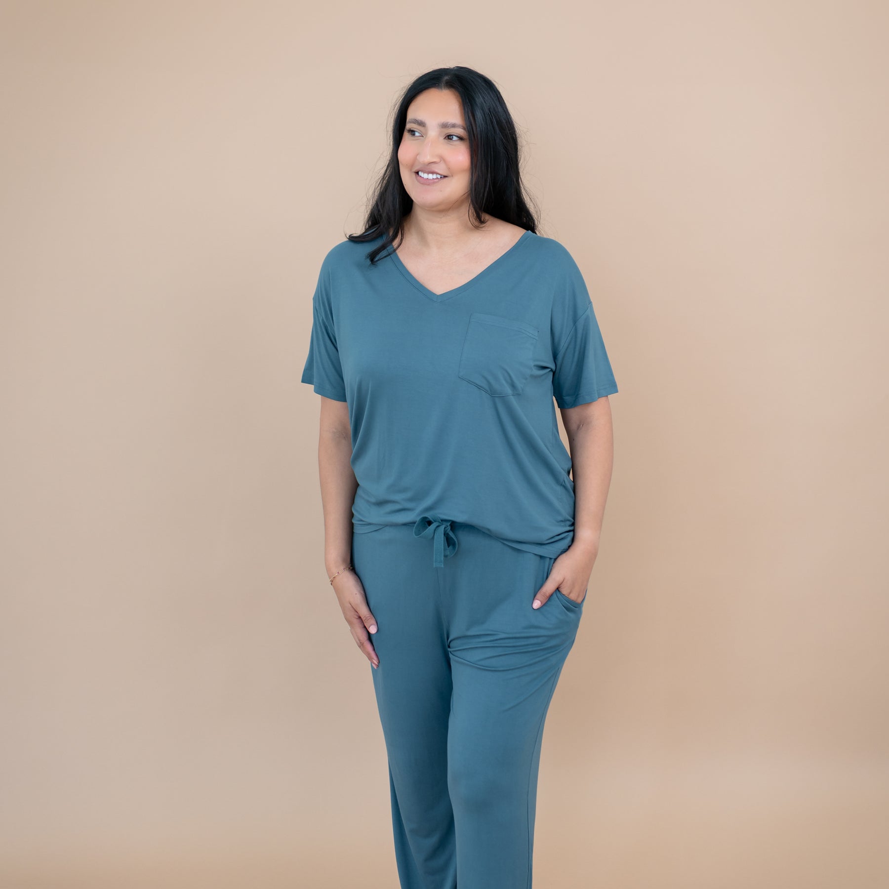 Smiling model standing with hand in pocket of the Women's Lounge Pants in Atlantic paired with a matching women's v-neck