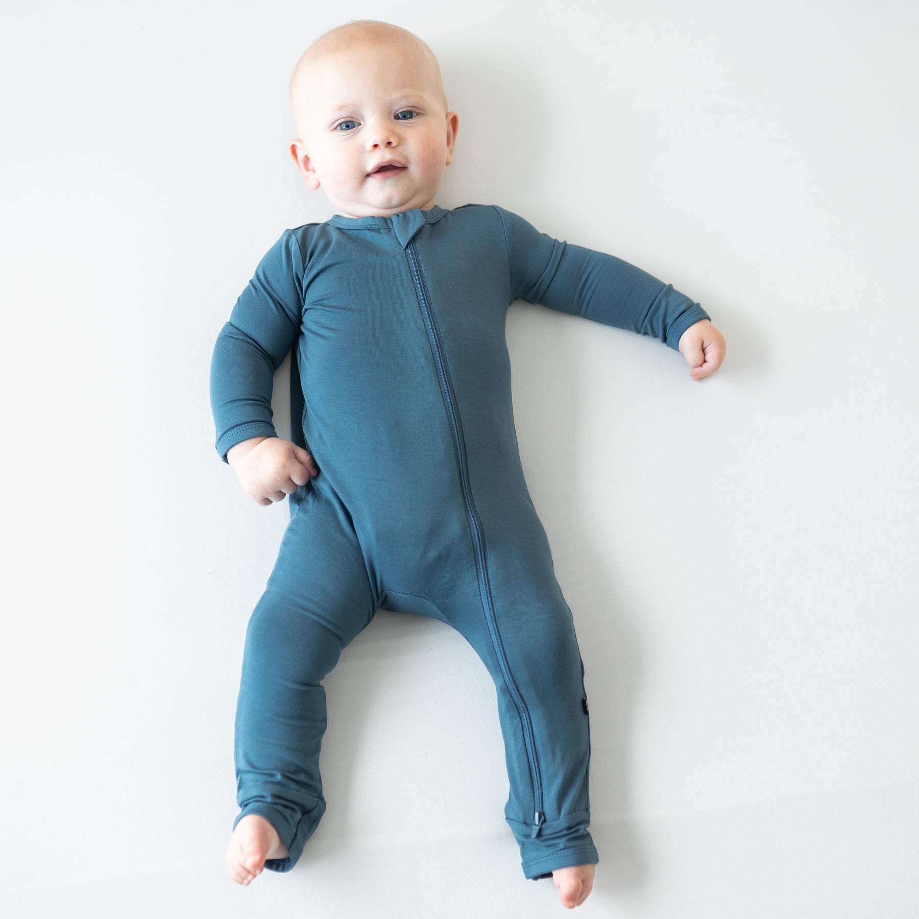 Infant laying down wearing the Zippered Romper in Atlantic