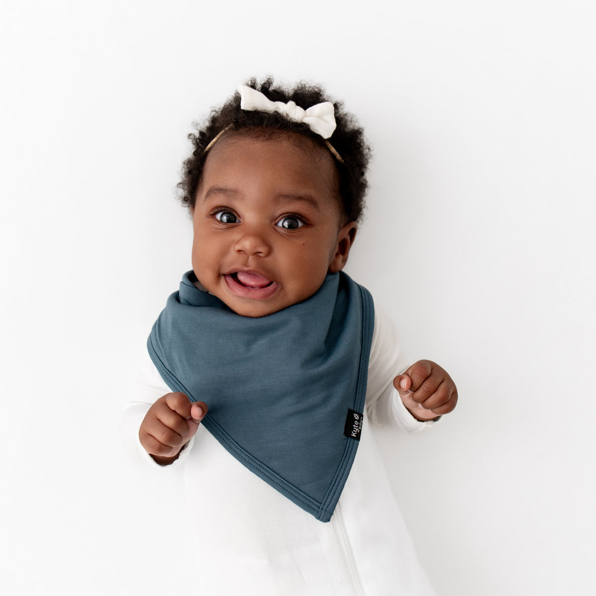 Infant girl wearing the Bib in Atlantic paired with a Cloud Zipper romper and Tiny Nylon Bow