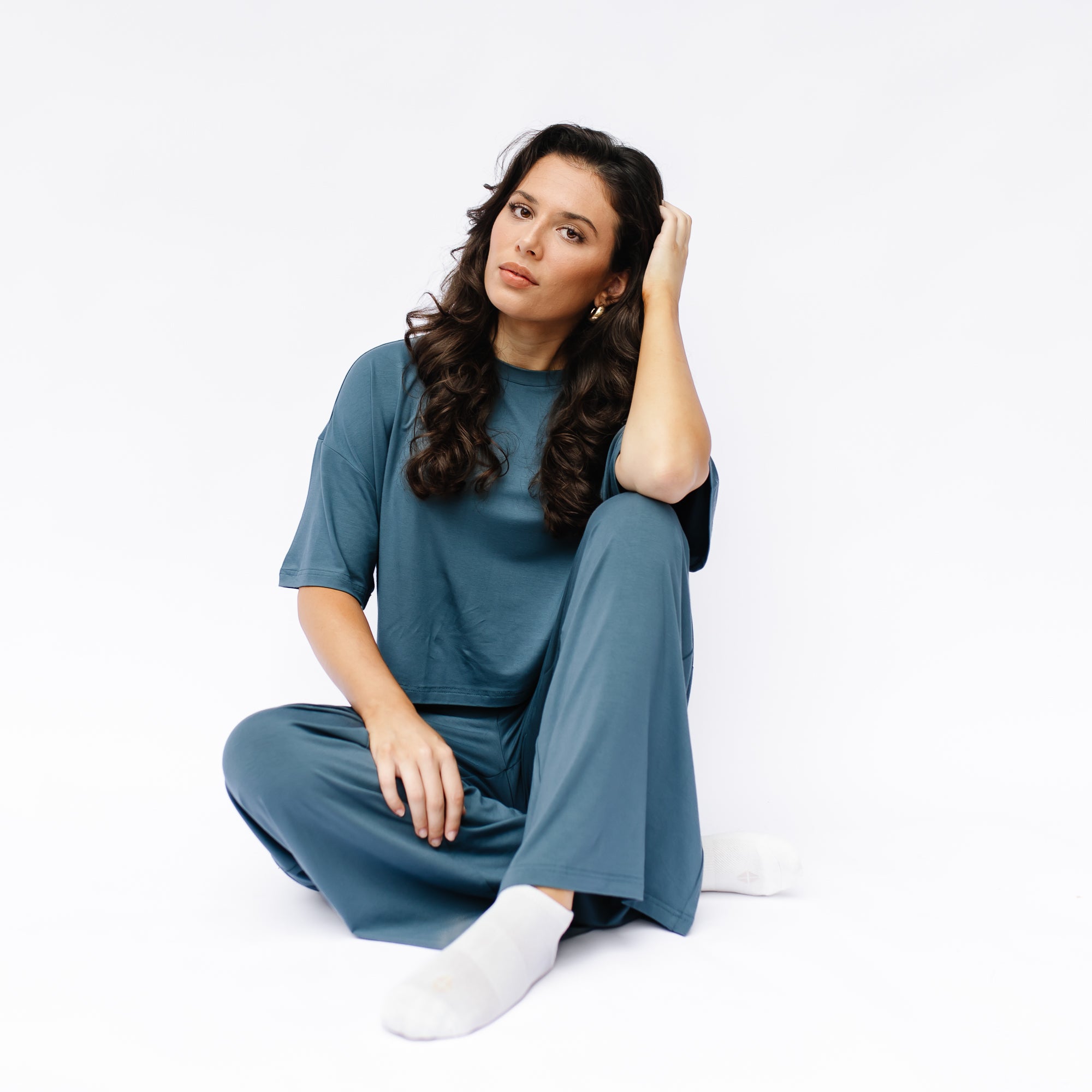 Female model sitting on the floor wearing the Women's Short Sleeve Tee in Atlantic with matching wide leg pants