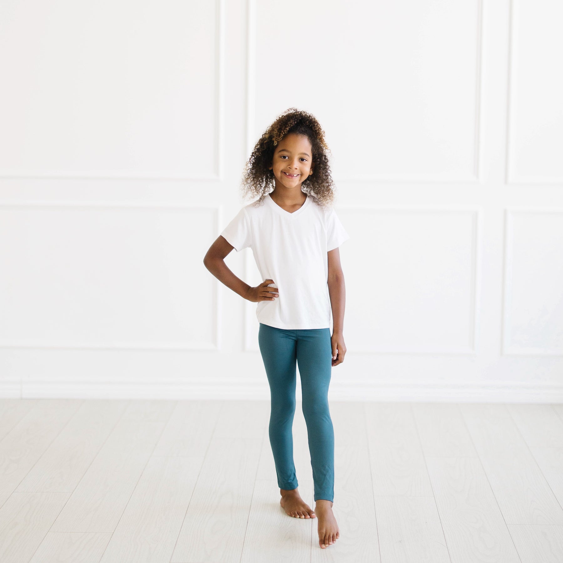 Kid standing with one hand on hip wearing the Toddler Leggings in Atlantic and Snow V-neck