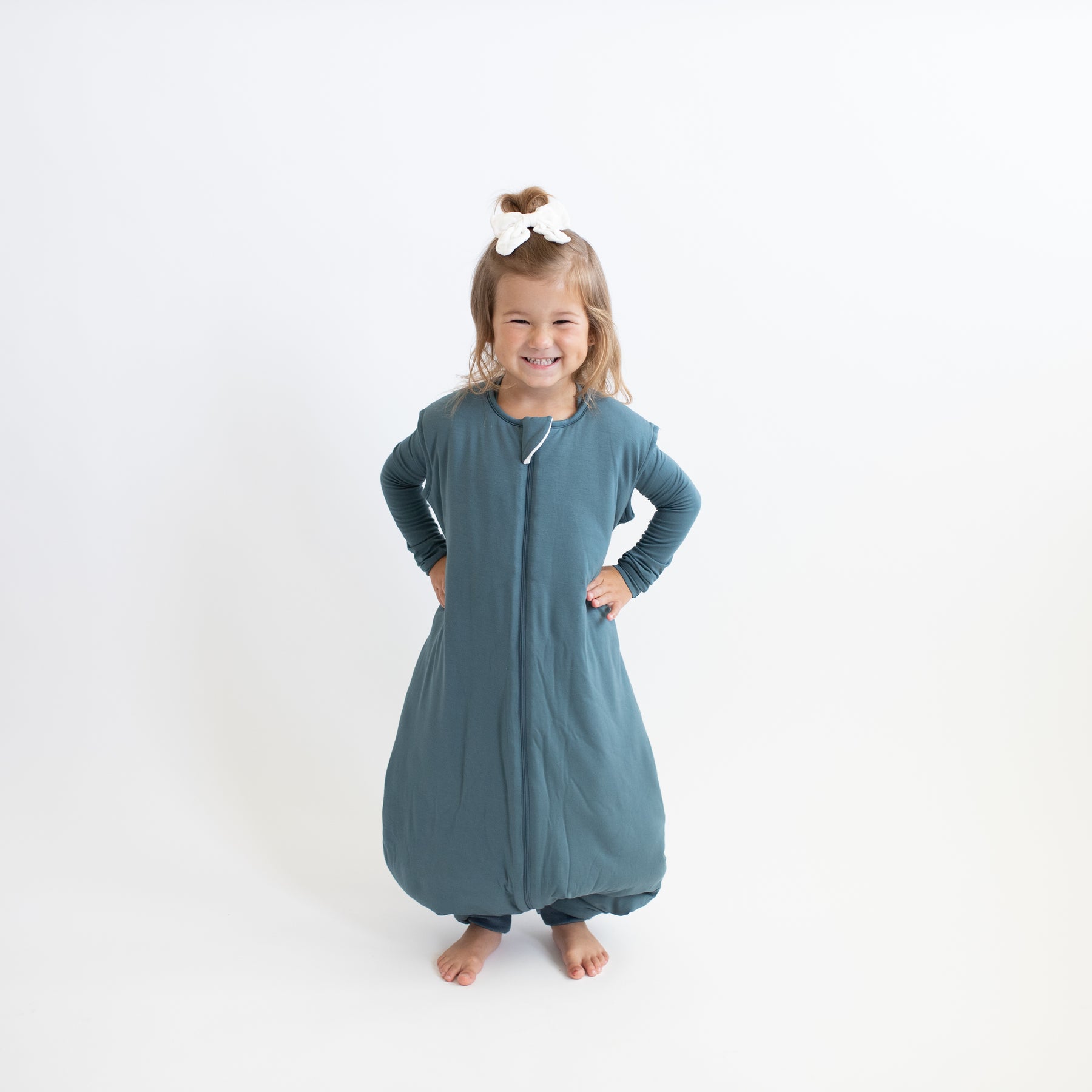 Smiling girl standing with hands on her hips wearing the Sleep Bag Walker in Atlantic 2.5