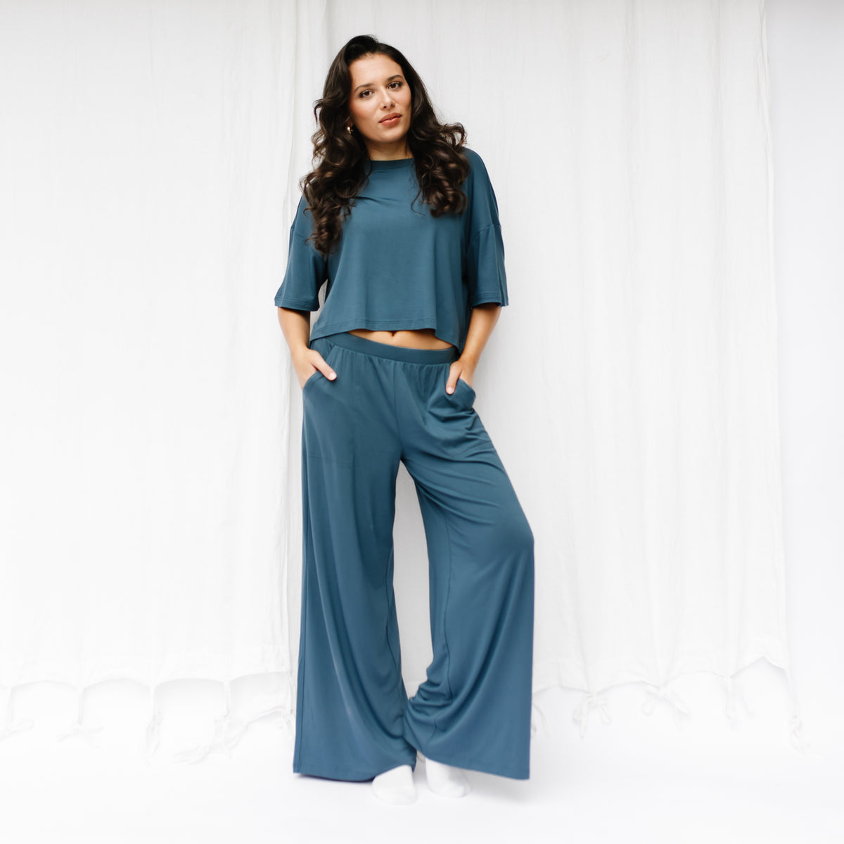 Female model standing in front of a white backdrop wearing the Women's Wide Leg Pant in Atlantic and matching Short Sleeve Tee