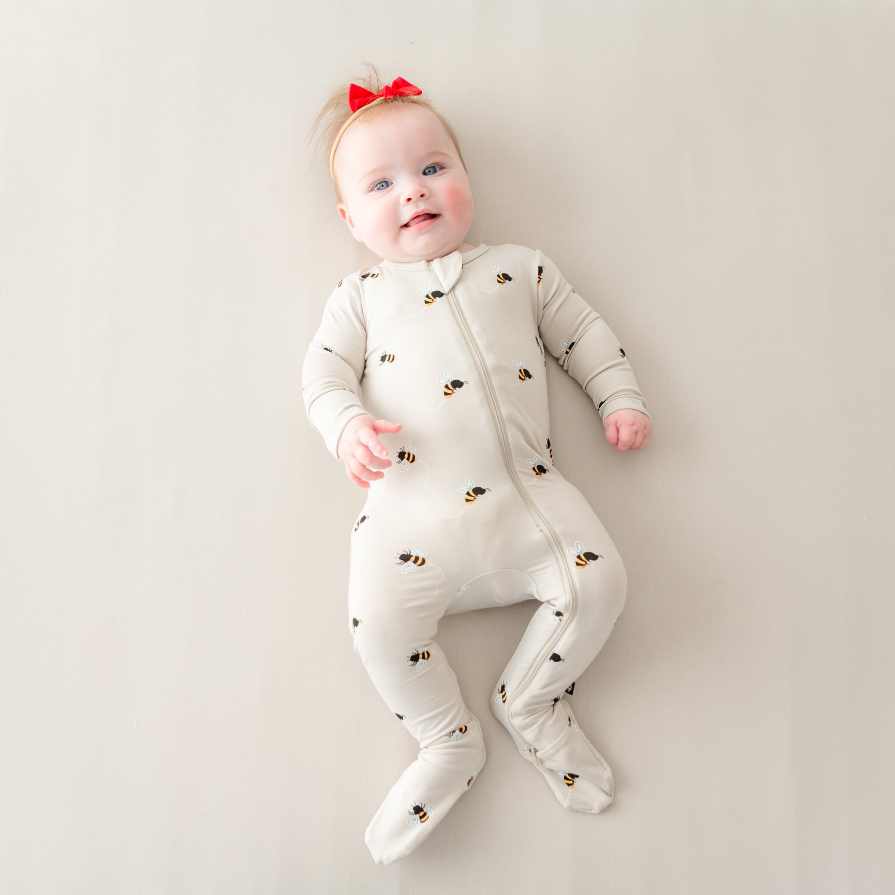 Baby laying down wearing Bee Mine Zippered Footie