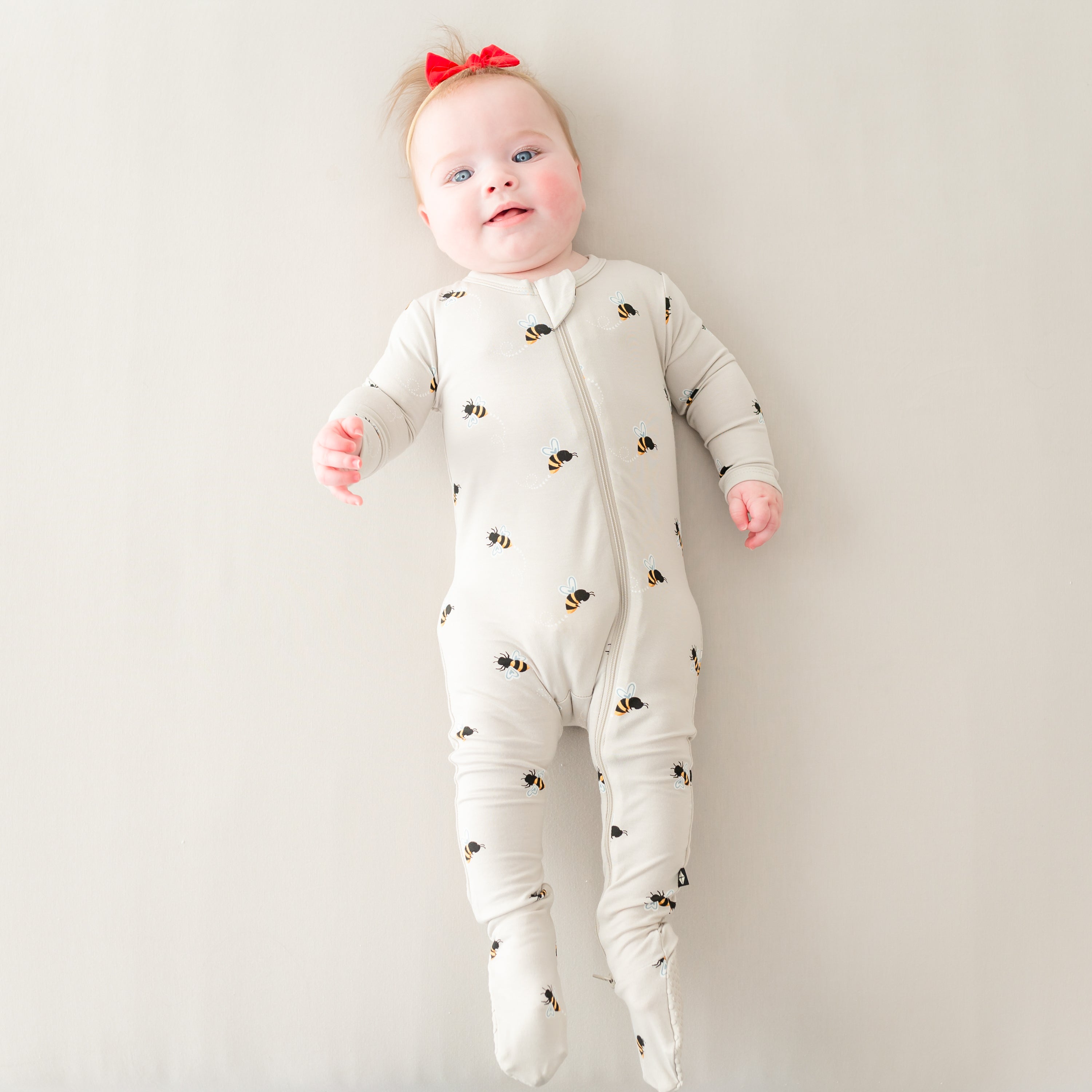 Baby laying down wearing Bee Mine Zippered Footie