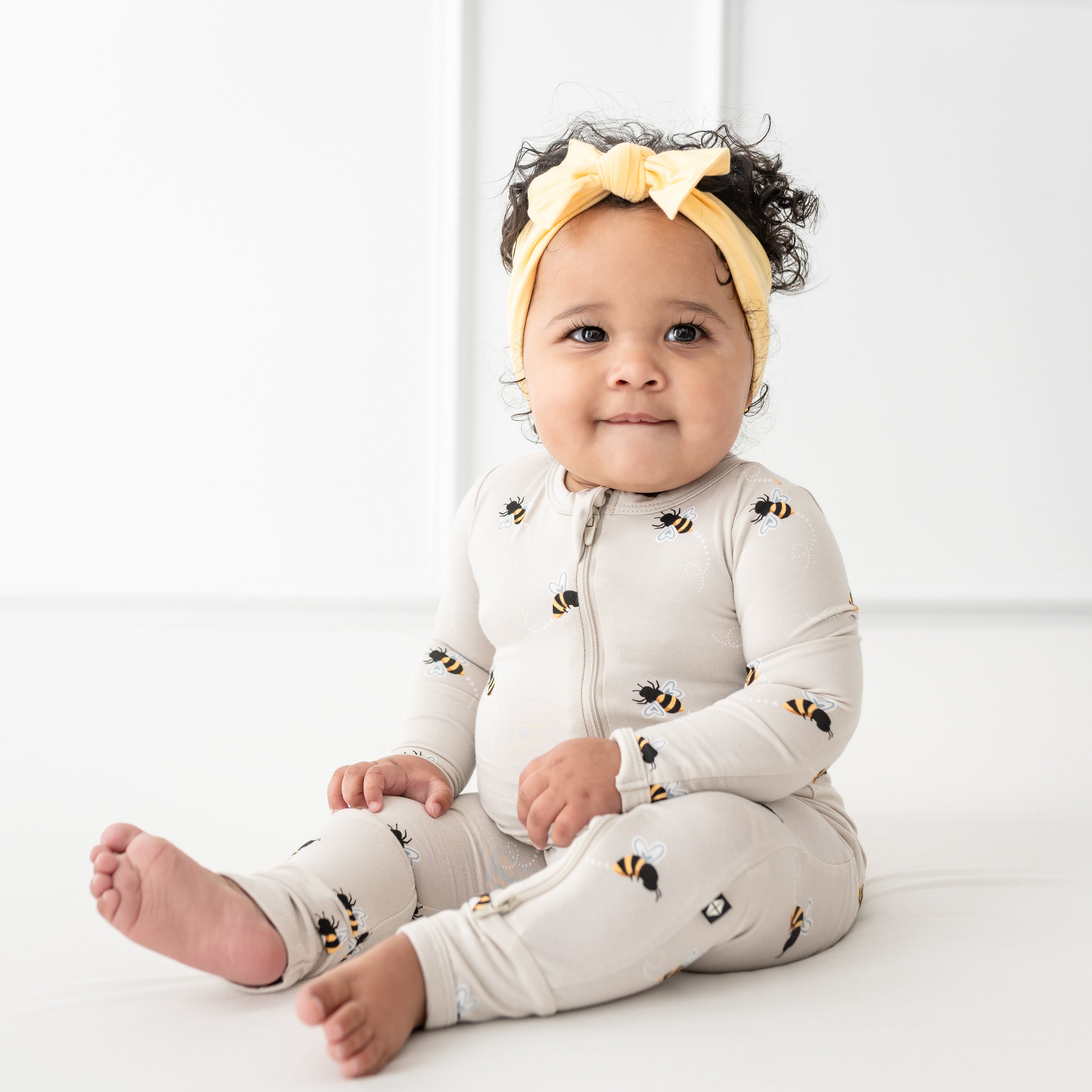 Baby sitting wearing Bee Mine zippered romper