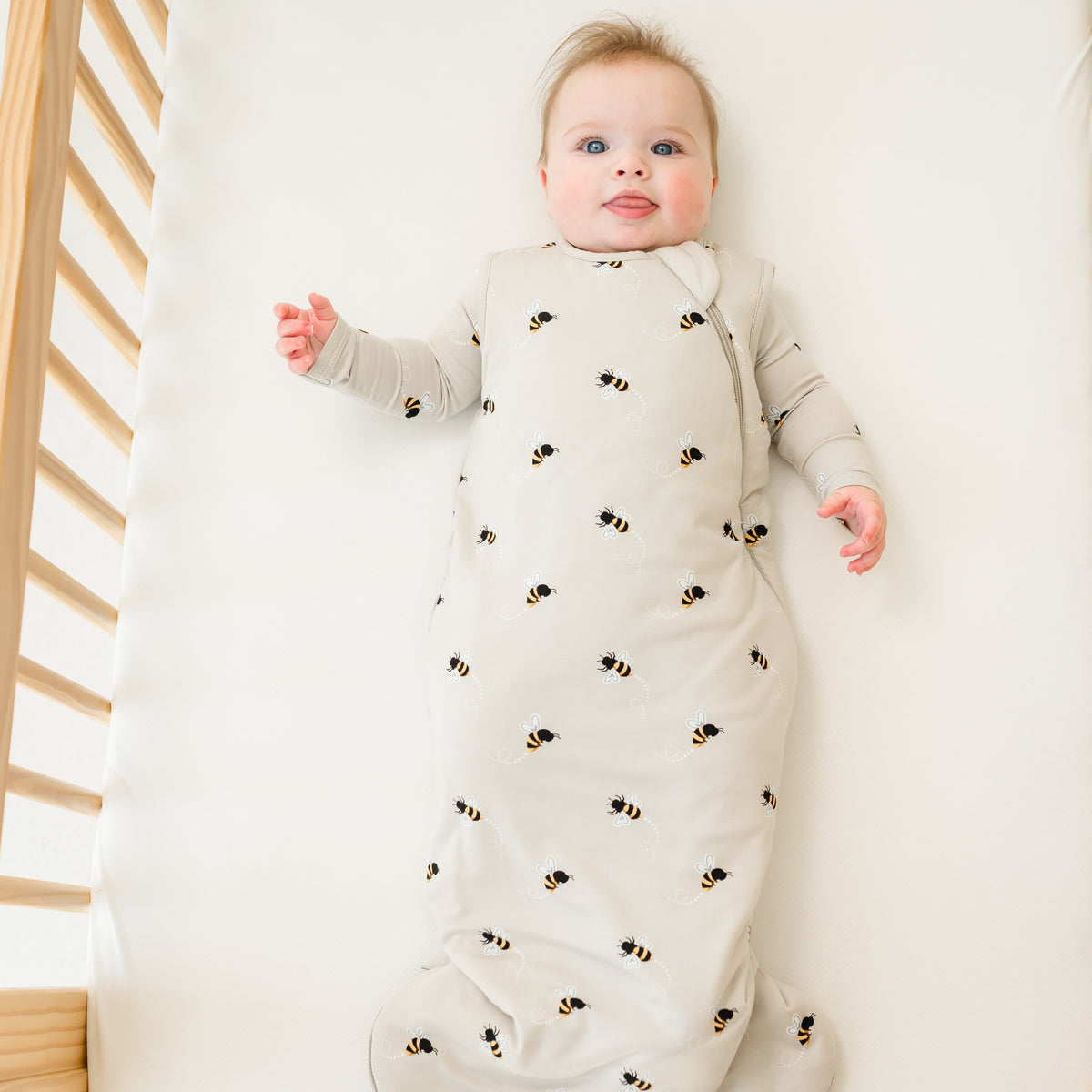 Baby wearing sleep bag in bee mine laying in a crib