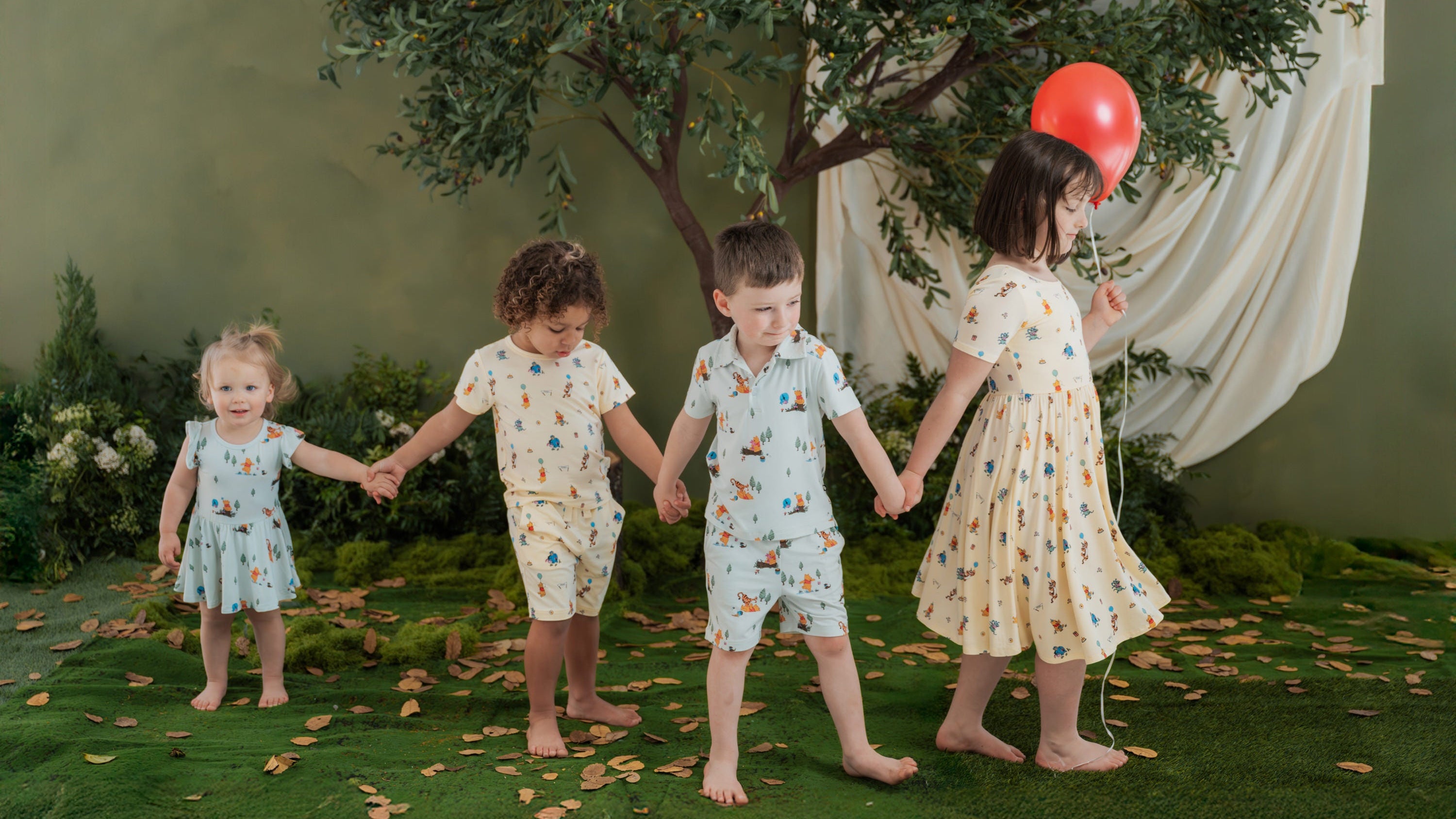 4 children wearing Disney Winnie the Pooh apparel in a wood setting 
