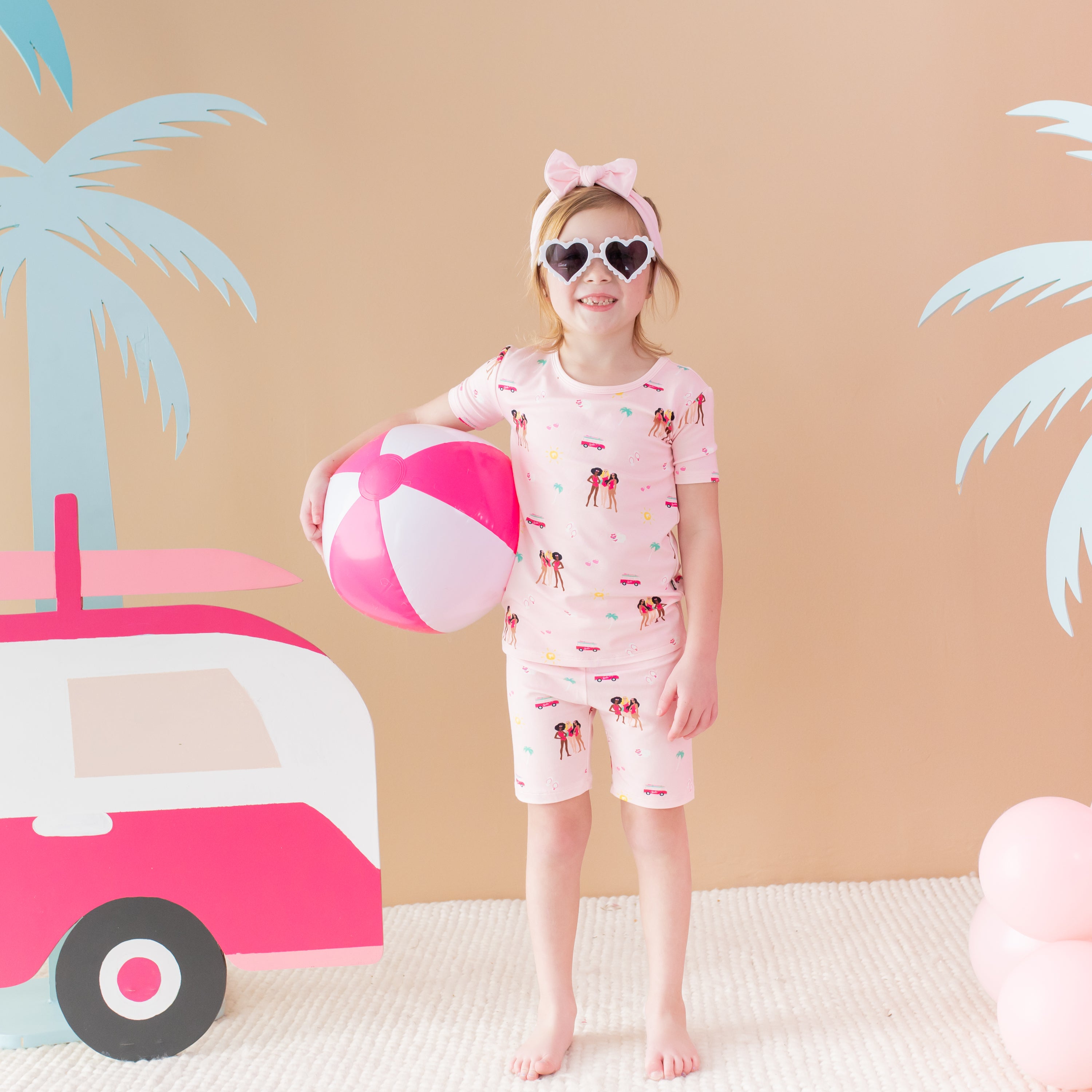 Child modeling Short Sleeve Pajamas in Barbie™ Beach with beach ball