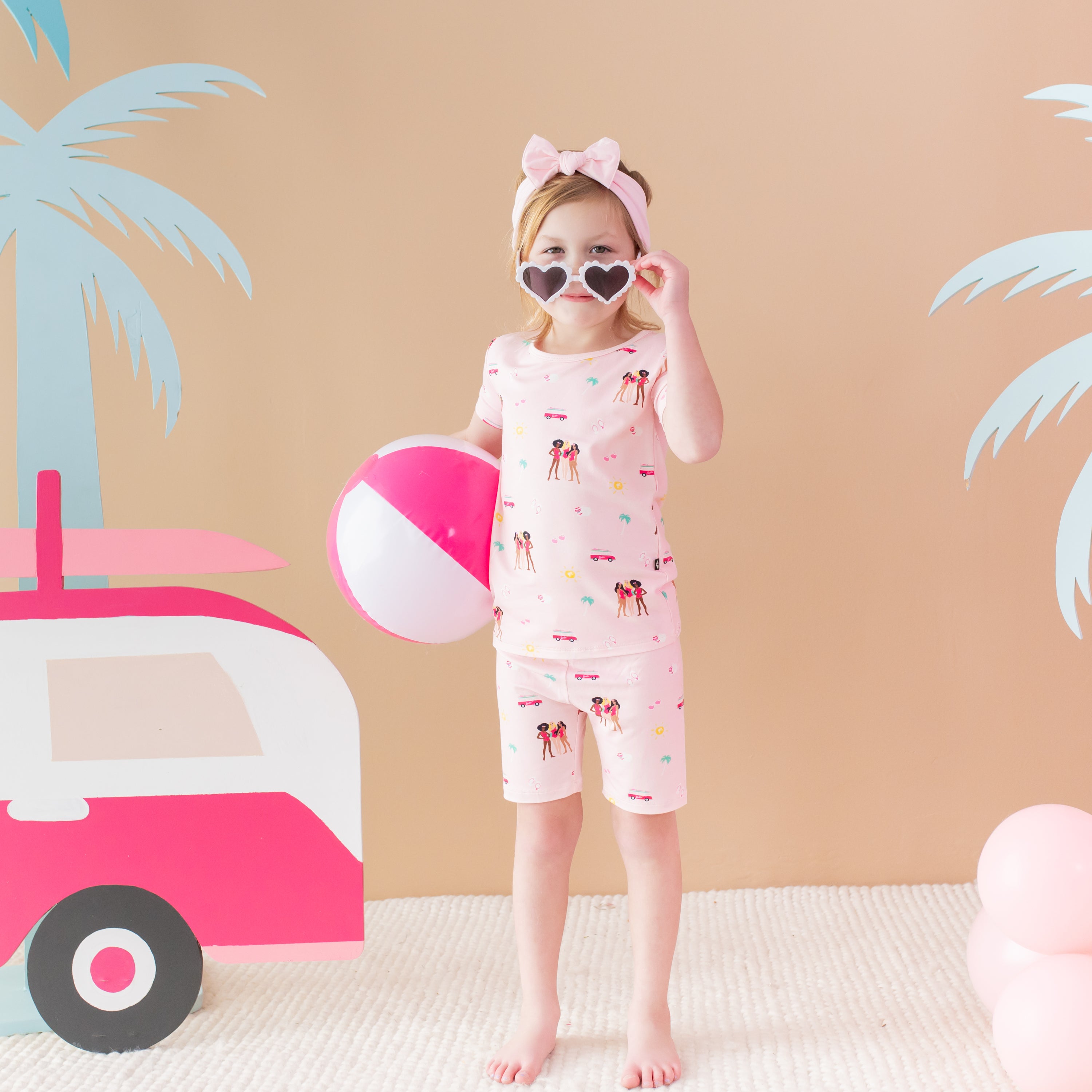 Child modeling Short Sleeve Pajamas in Barbie™ Beach with beach ball and sunglasses