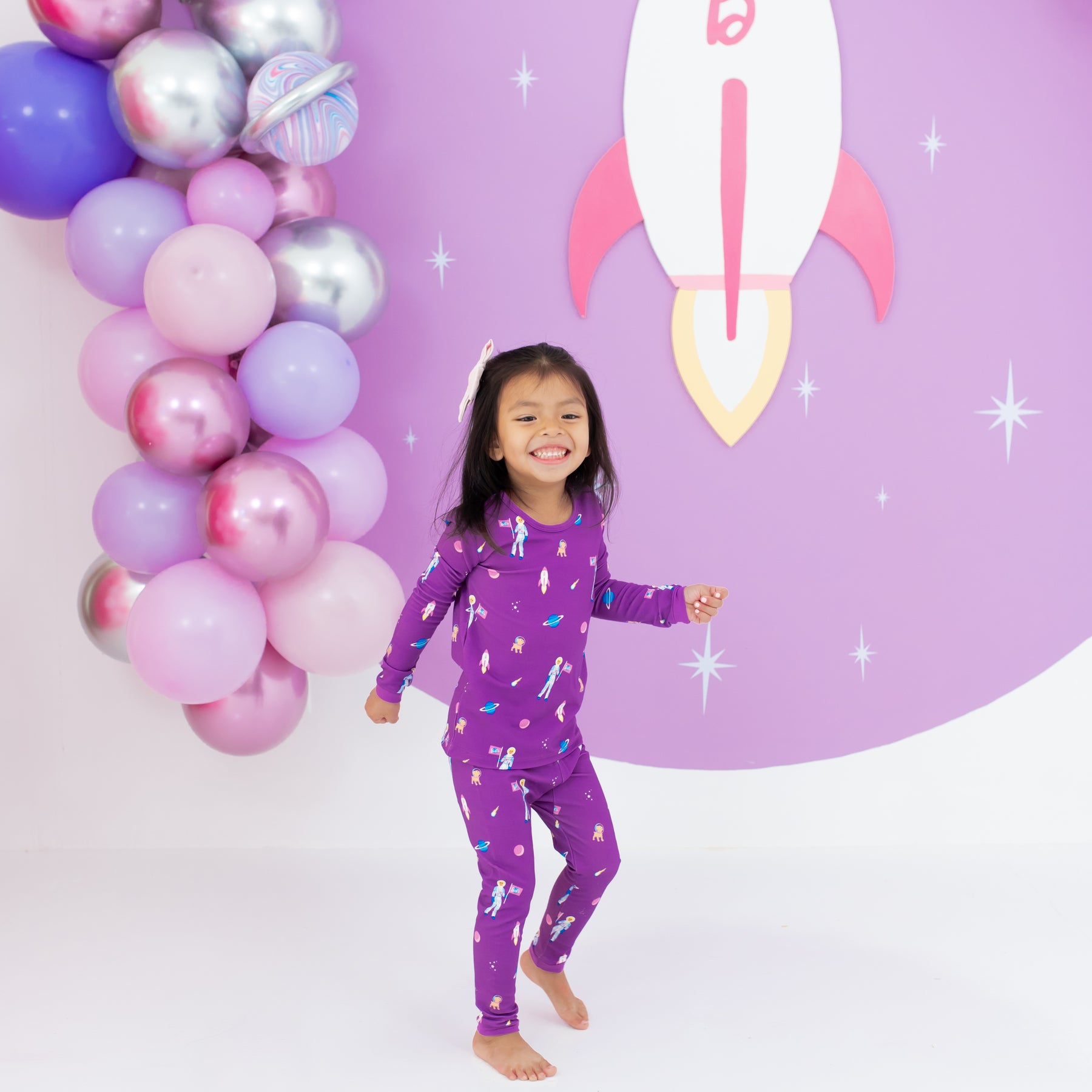 Toddler in Long Sleeve Pajamas in Barbie™ Astronaut with a balloon backdrop 