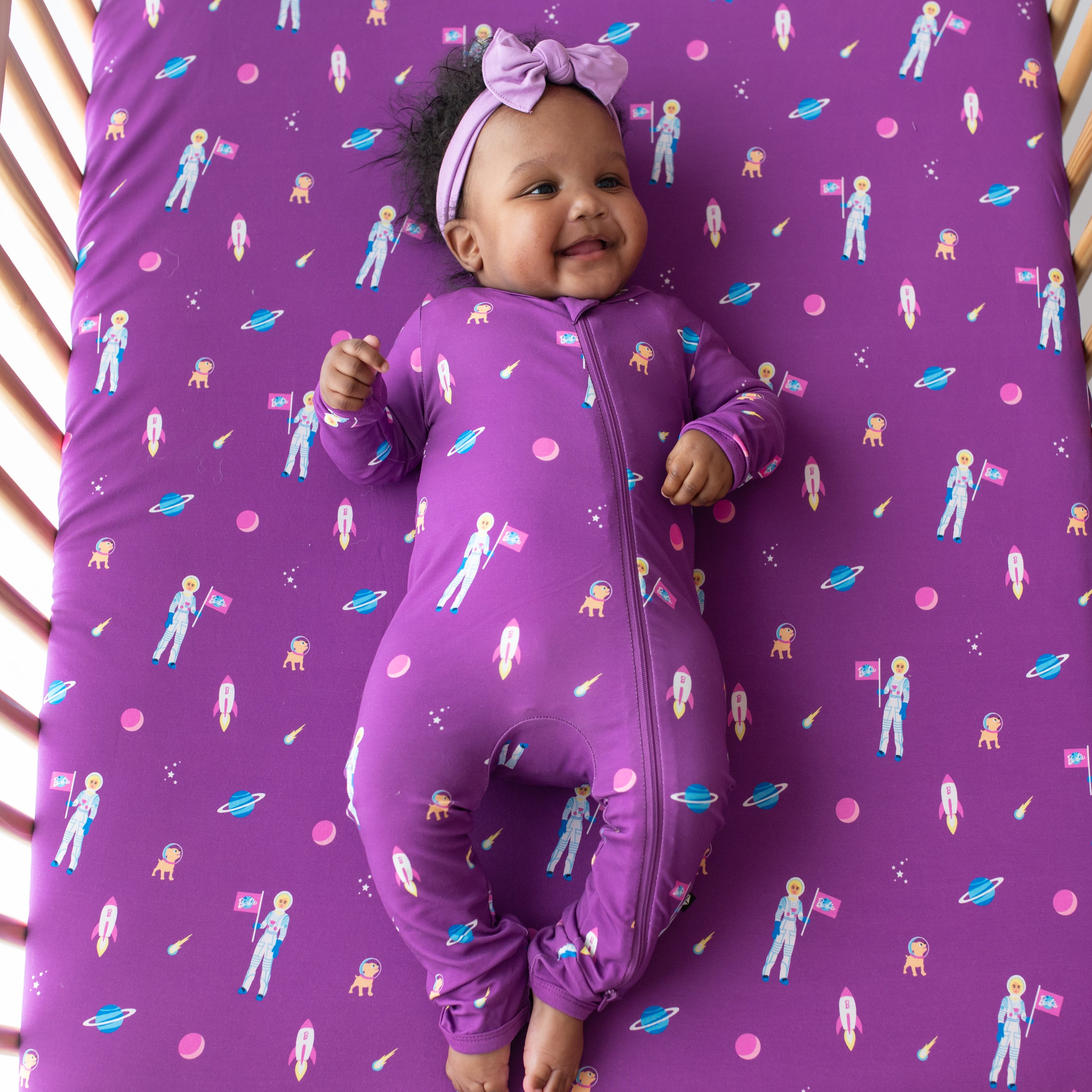 Baby in a crib with Crib Sheet in Barbie™ Astronaut on wearing Barbie™ Astronaut  zippered romper