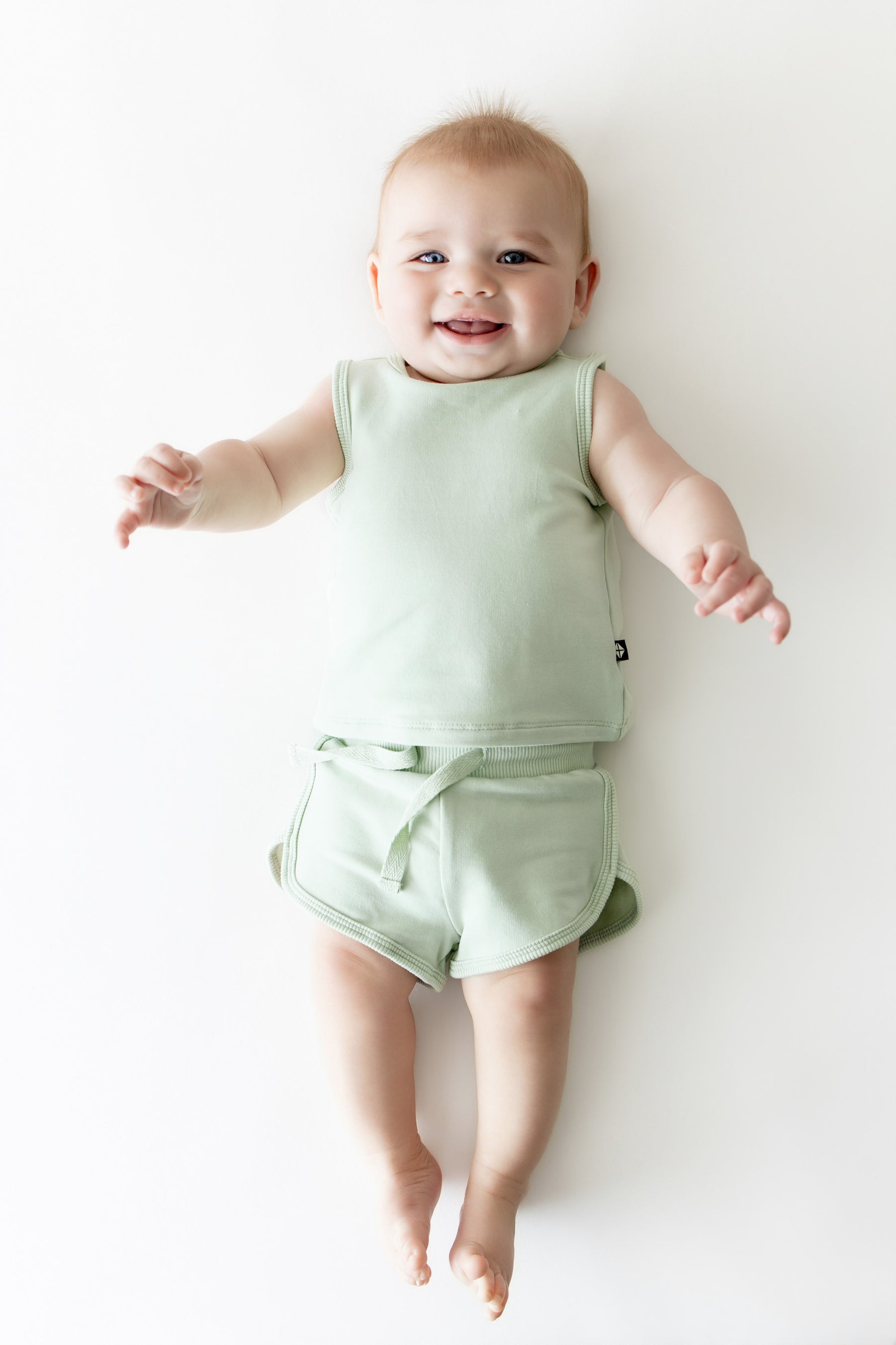 Young infant laying on a light surface wearing the Tank Jogger Set in Basil