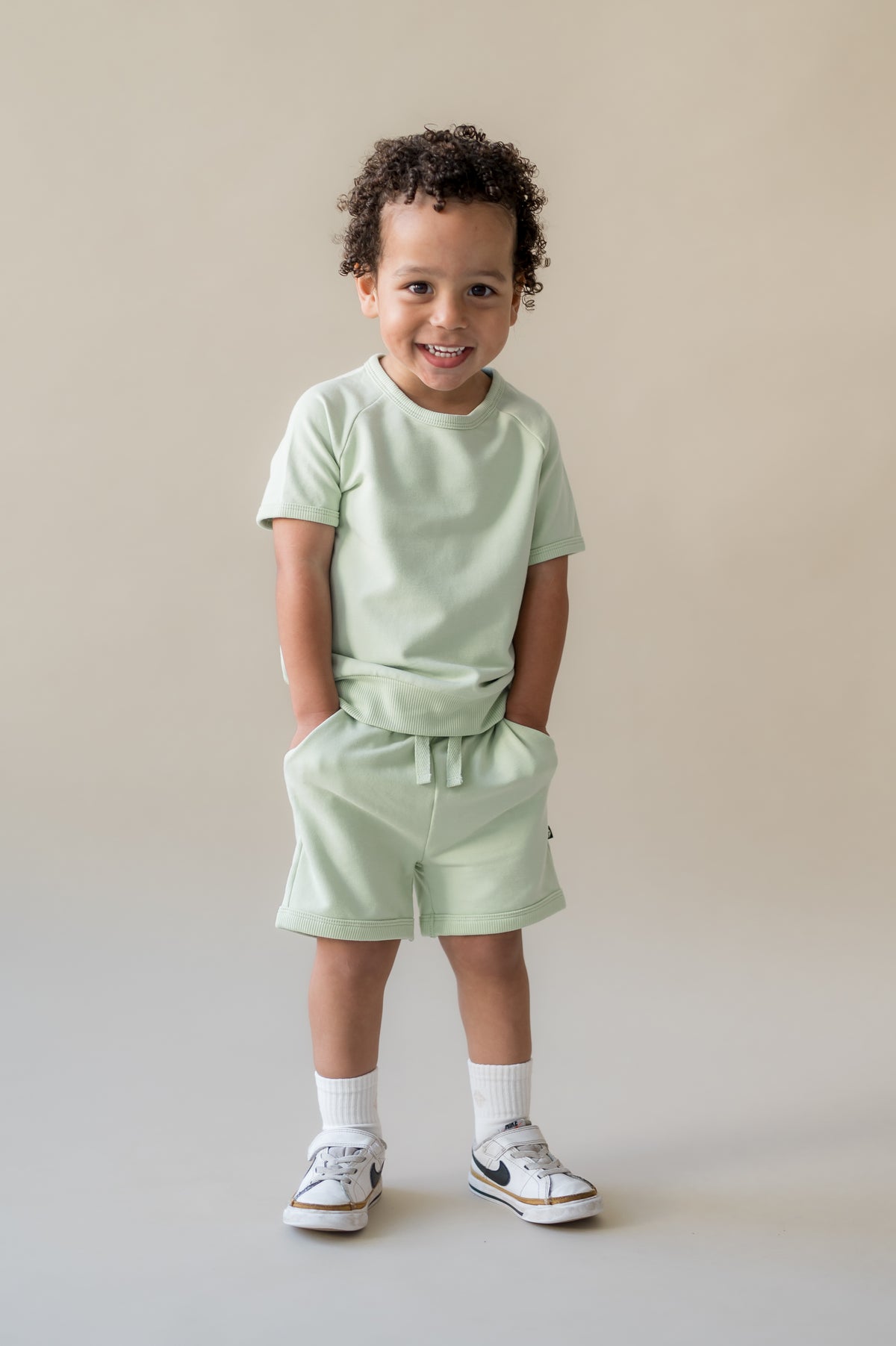 Young boy standing with his hands in the pockets of the Short Sleeve Jogger Set in Basil
