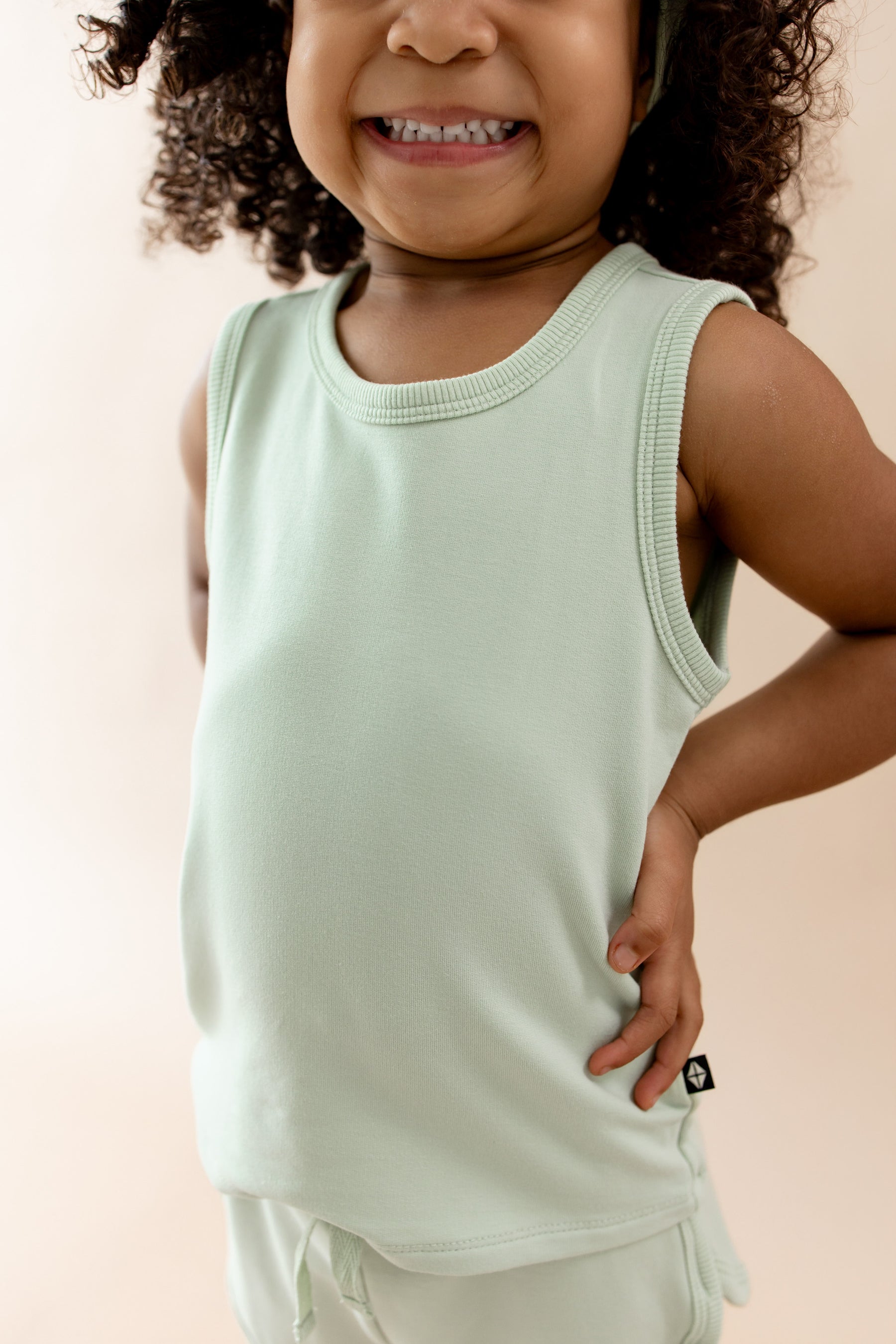 Close up of the shirt of the Tank Jogger Set in Basil on a young model