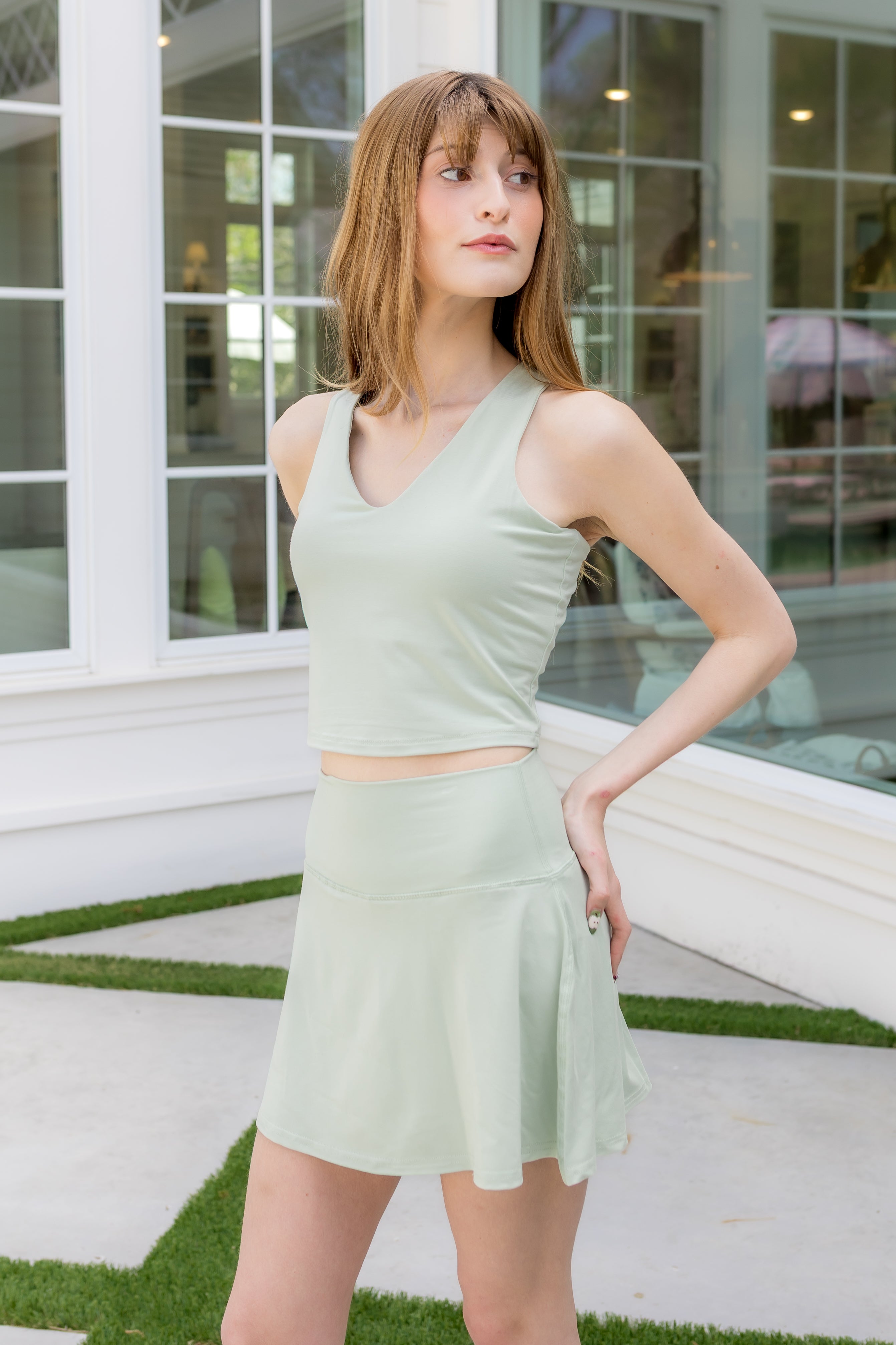 Female model posing wearing the Bamboo Flex Skort in Basil with matching bra tank