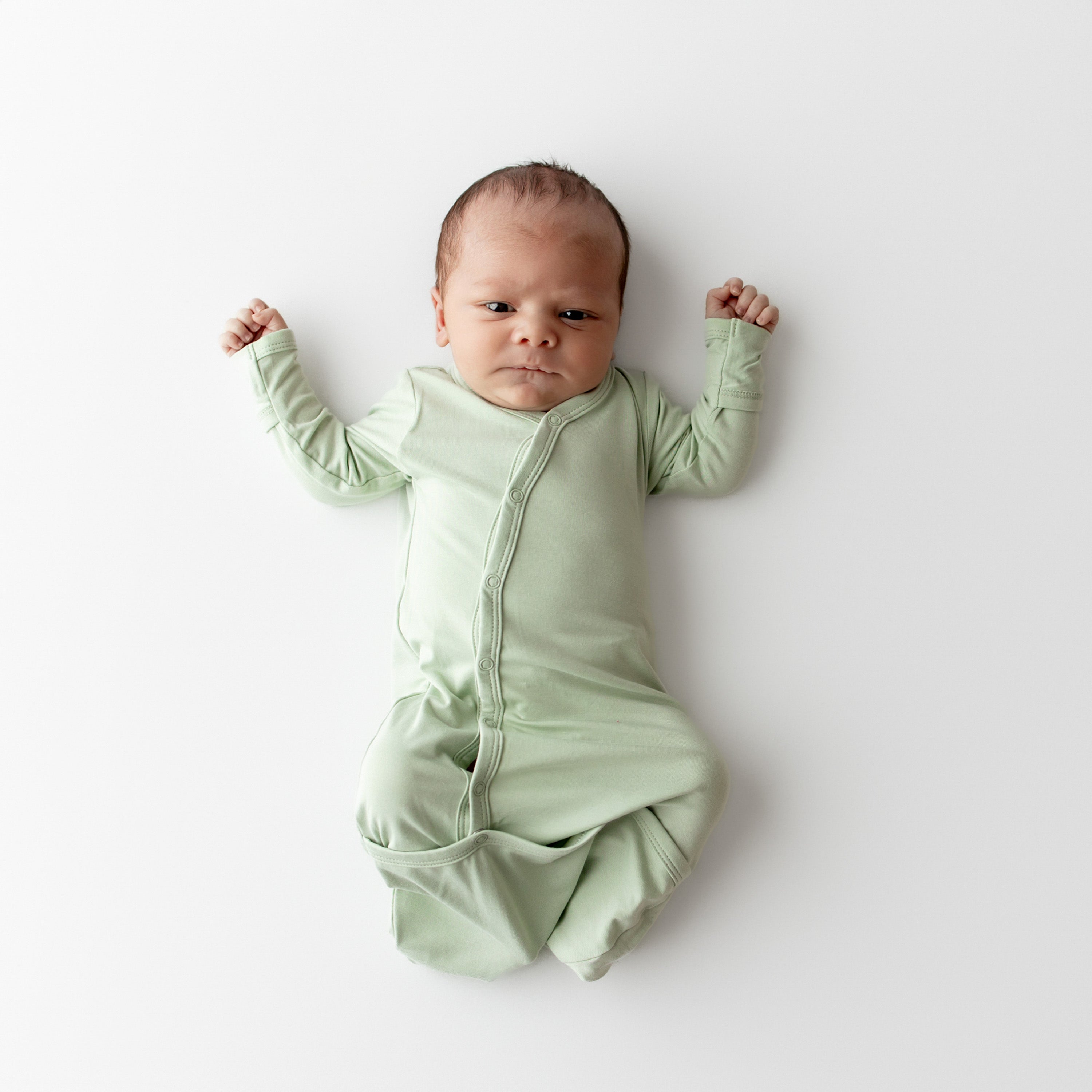 Baby wearing a light green bundler on a white background