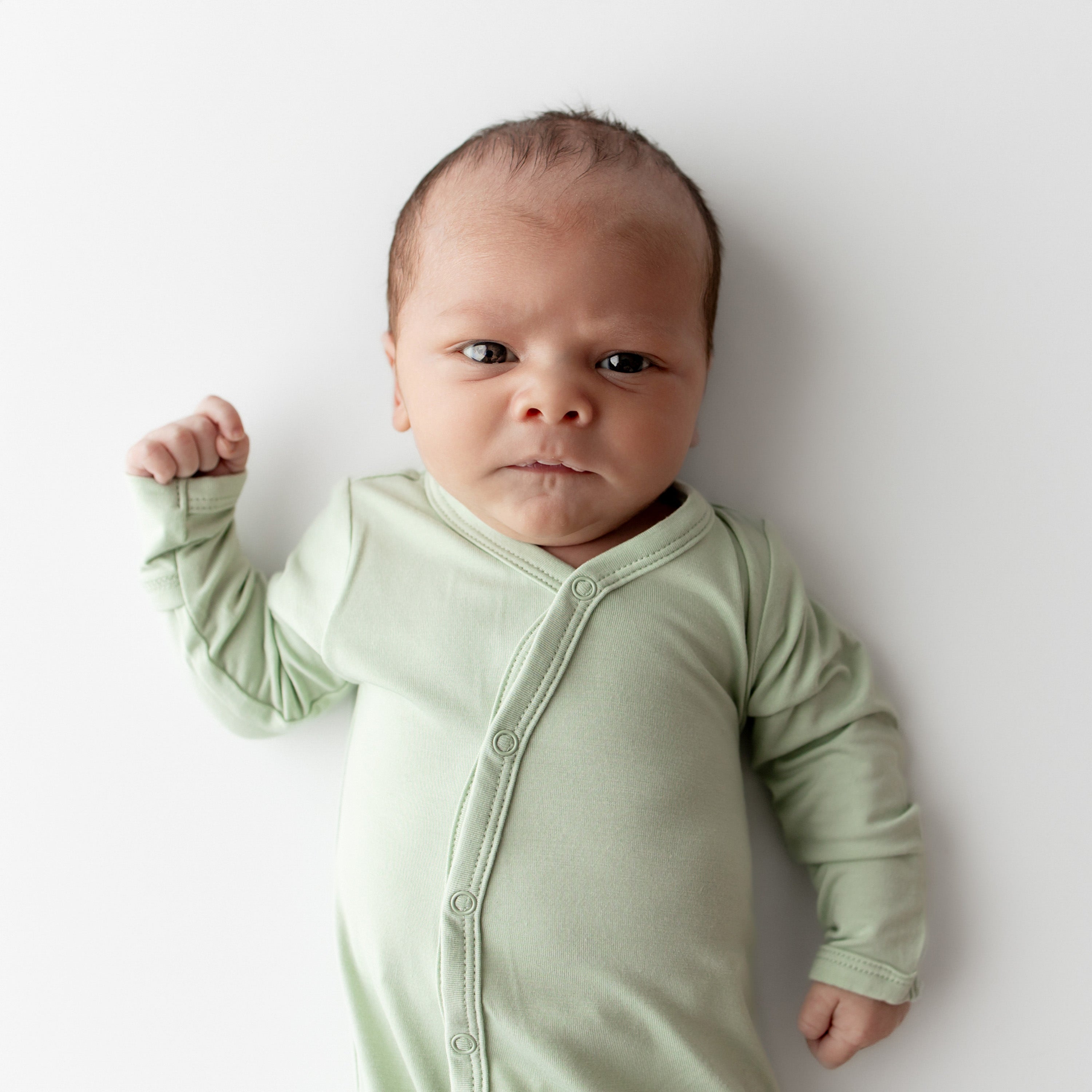 Baby wearing a light green bundler on a white background