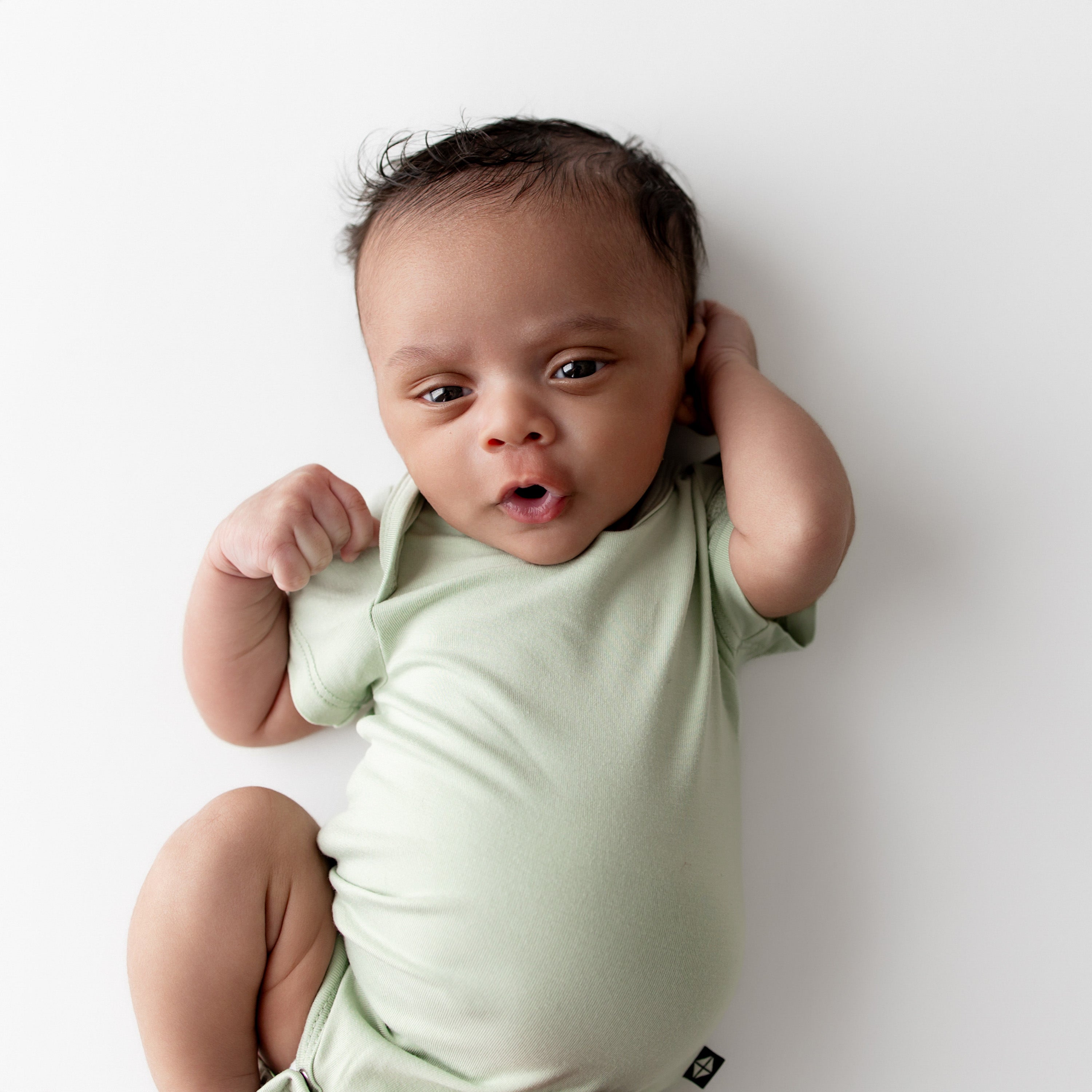 Baby wearing a light green onesie on a white background