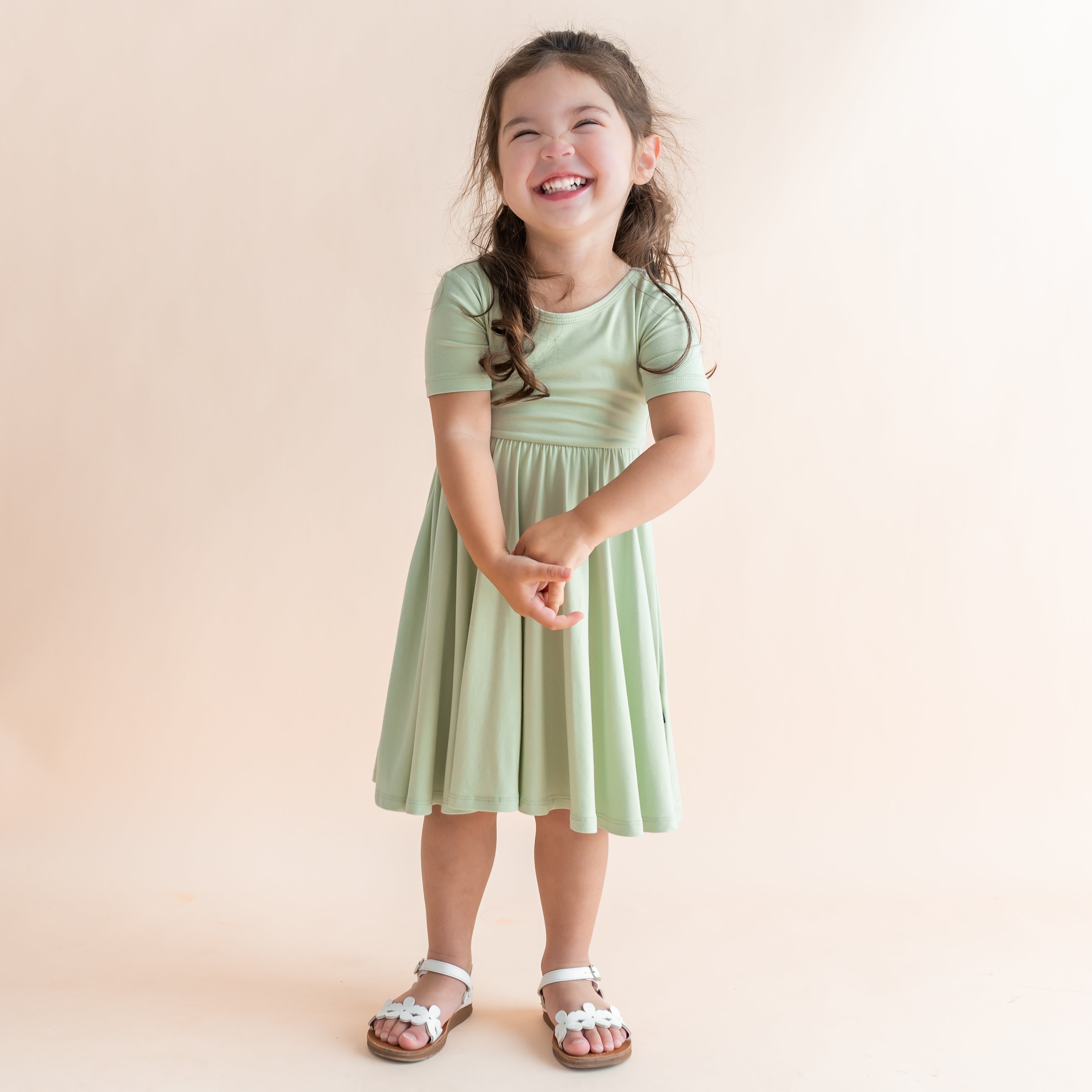 Young girl wearing a light green dress against a beige background