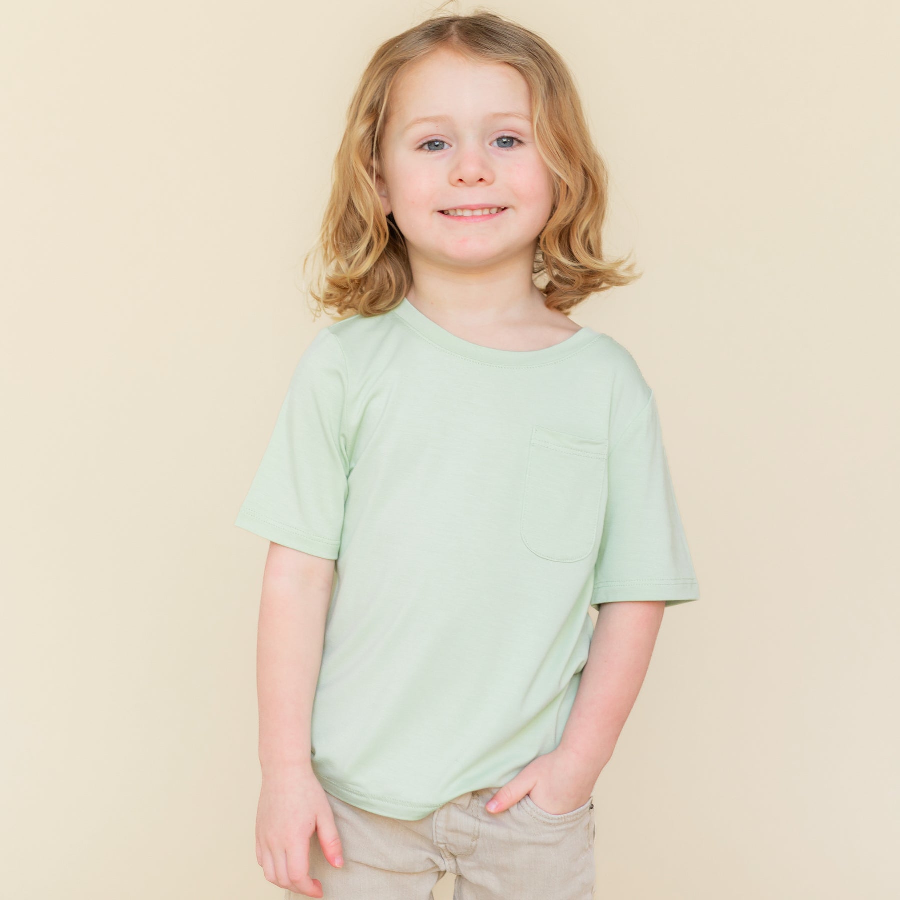 Young child wearing the Toddler Crew Neck Tee in Basil paired with a khaki colored short