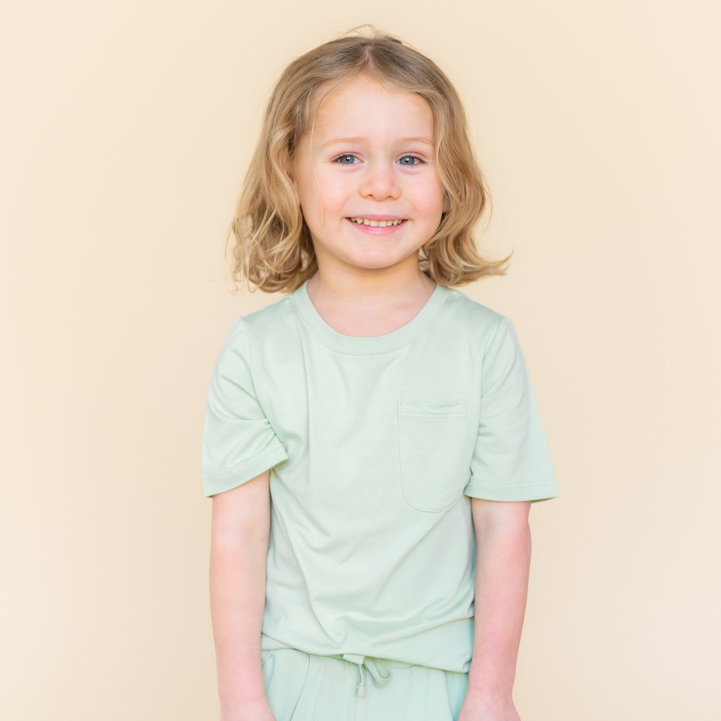 Young child modeling the Toddler Crew Neck Tee in Basil paired with matching drawstring shorts