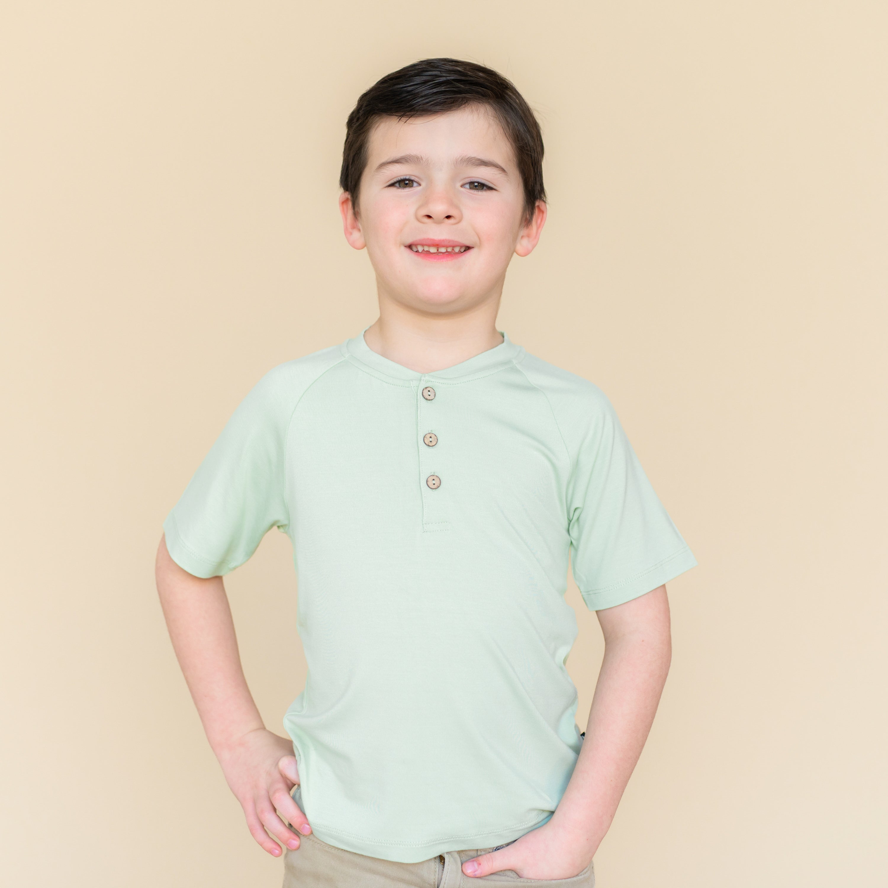Young boy modeling the Short Sleeve Toddler Henley Tee in Basil