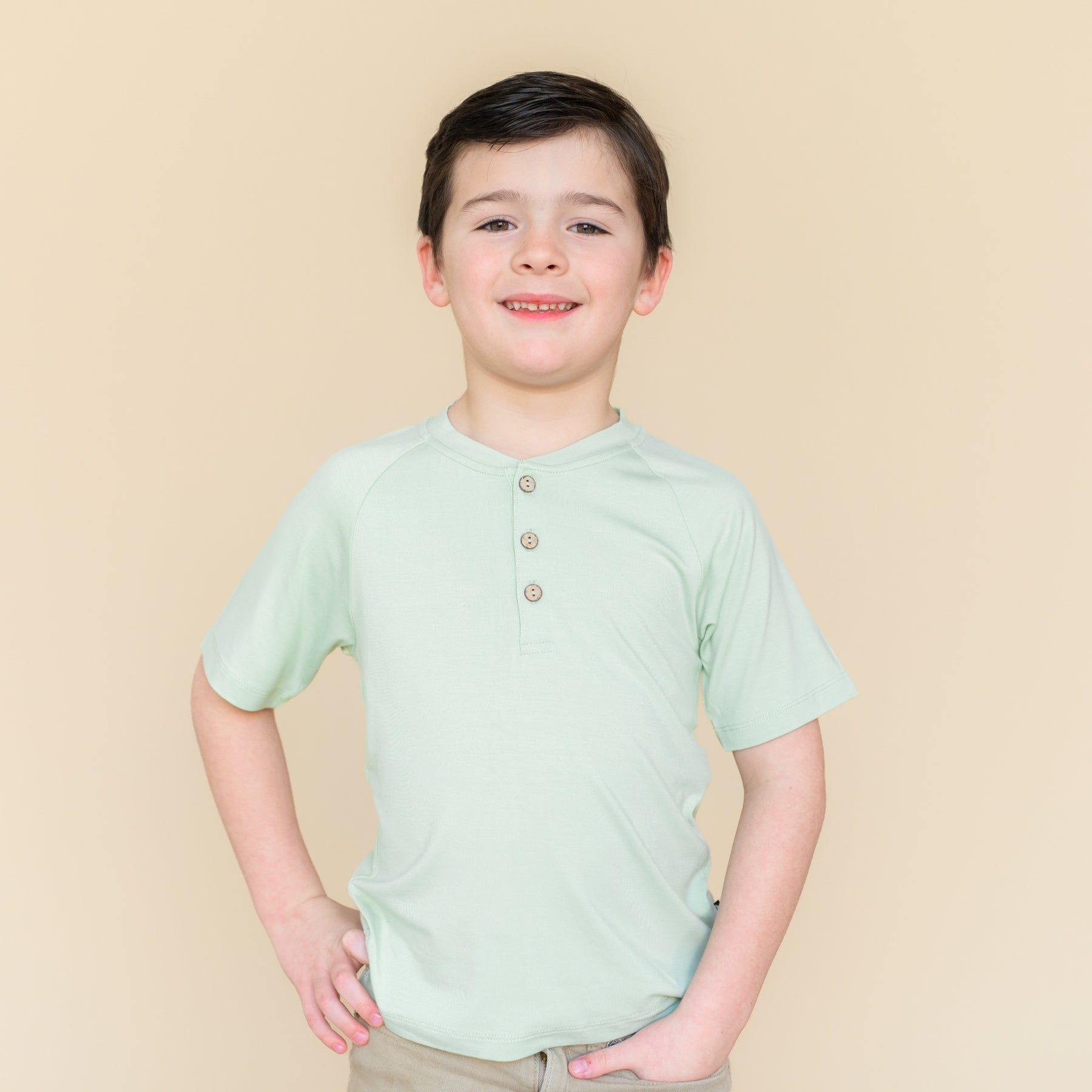 Young boy modeling the Short Sleeve Toddler Henley Tee in Basil