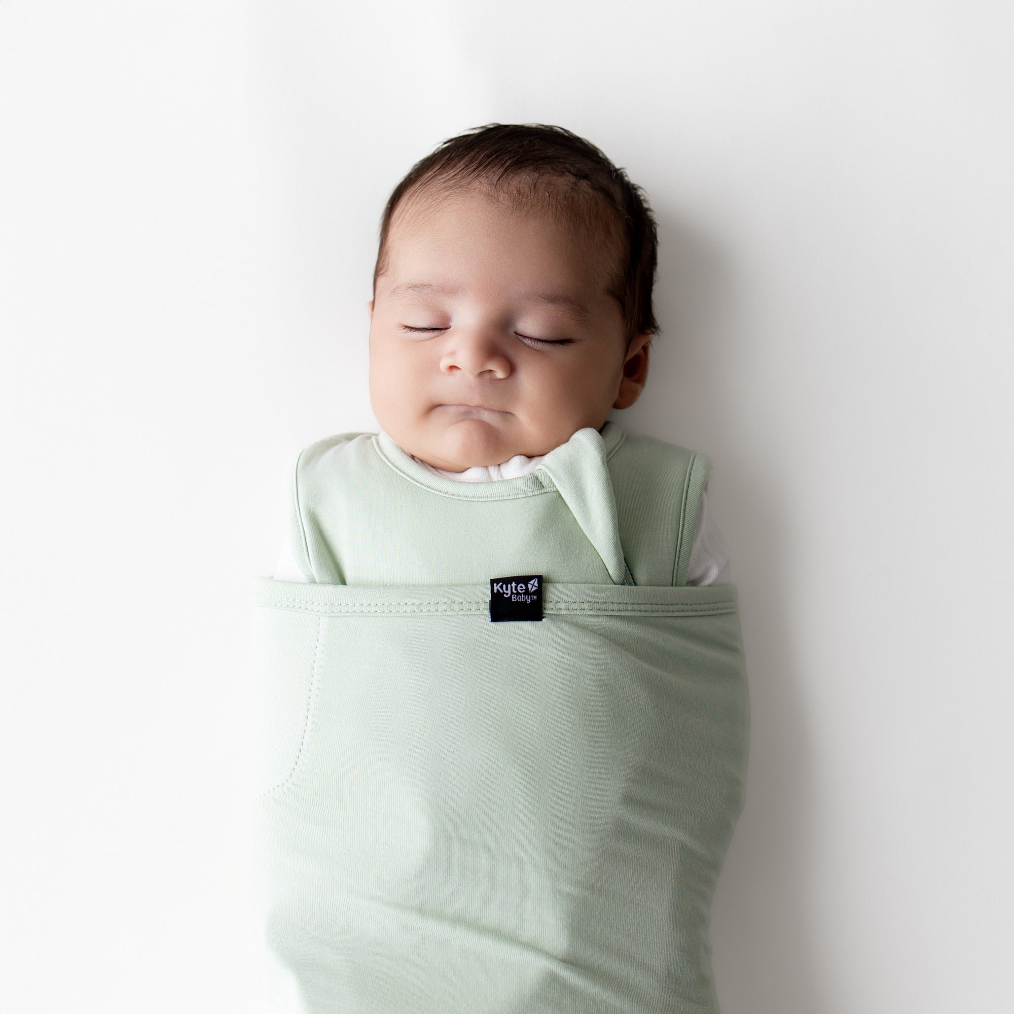 Close up of sleeping newborn swaddled in the Sleep Bag Swaddler in Basil 1.0