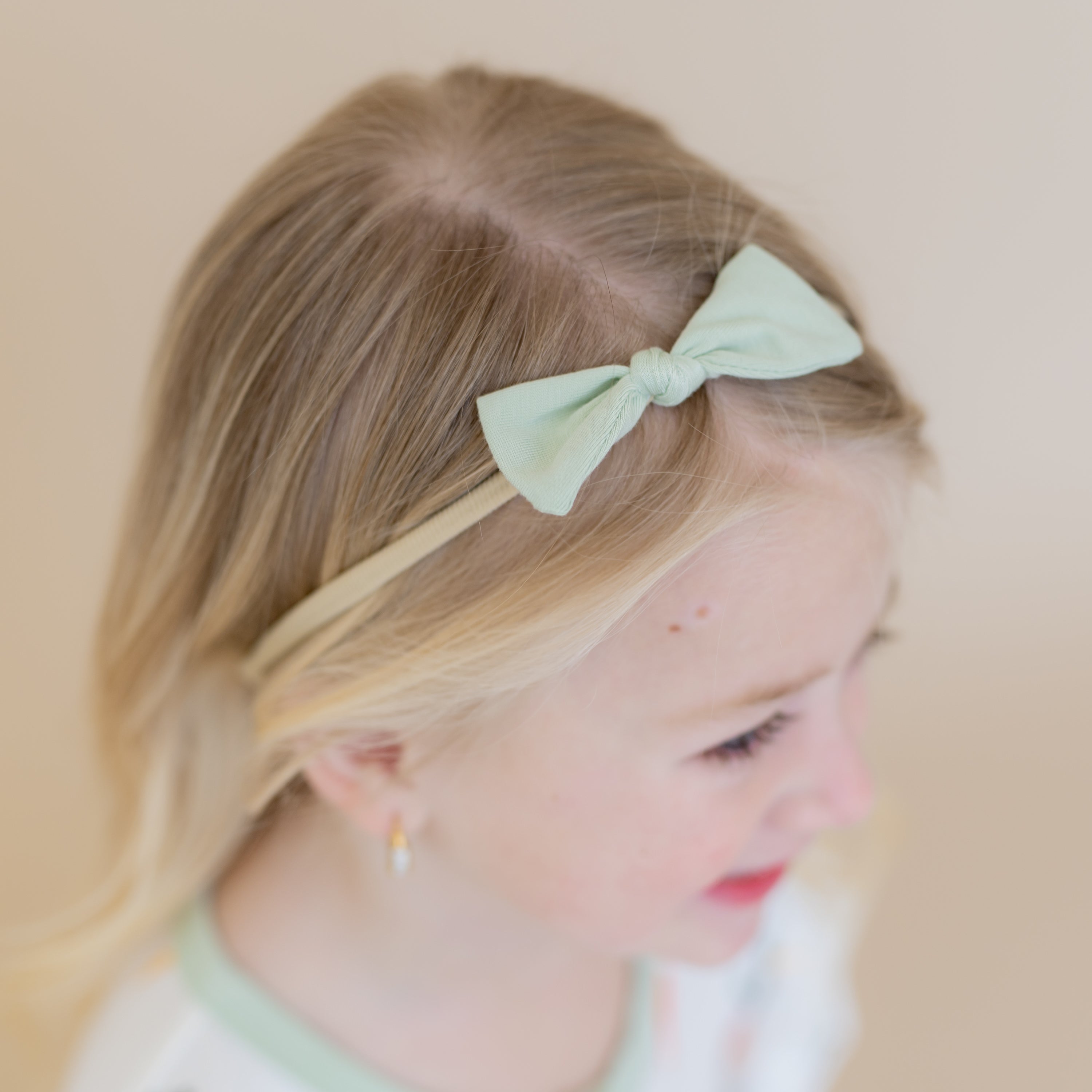 Close up of the Tiny Nylon Bow in Basil shown in a girls hair