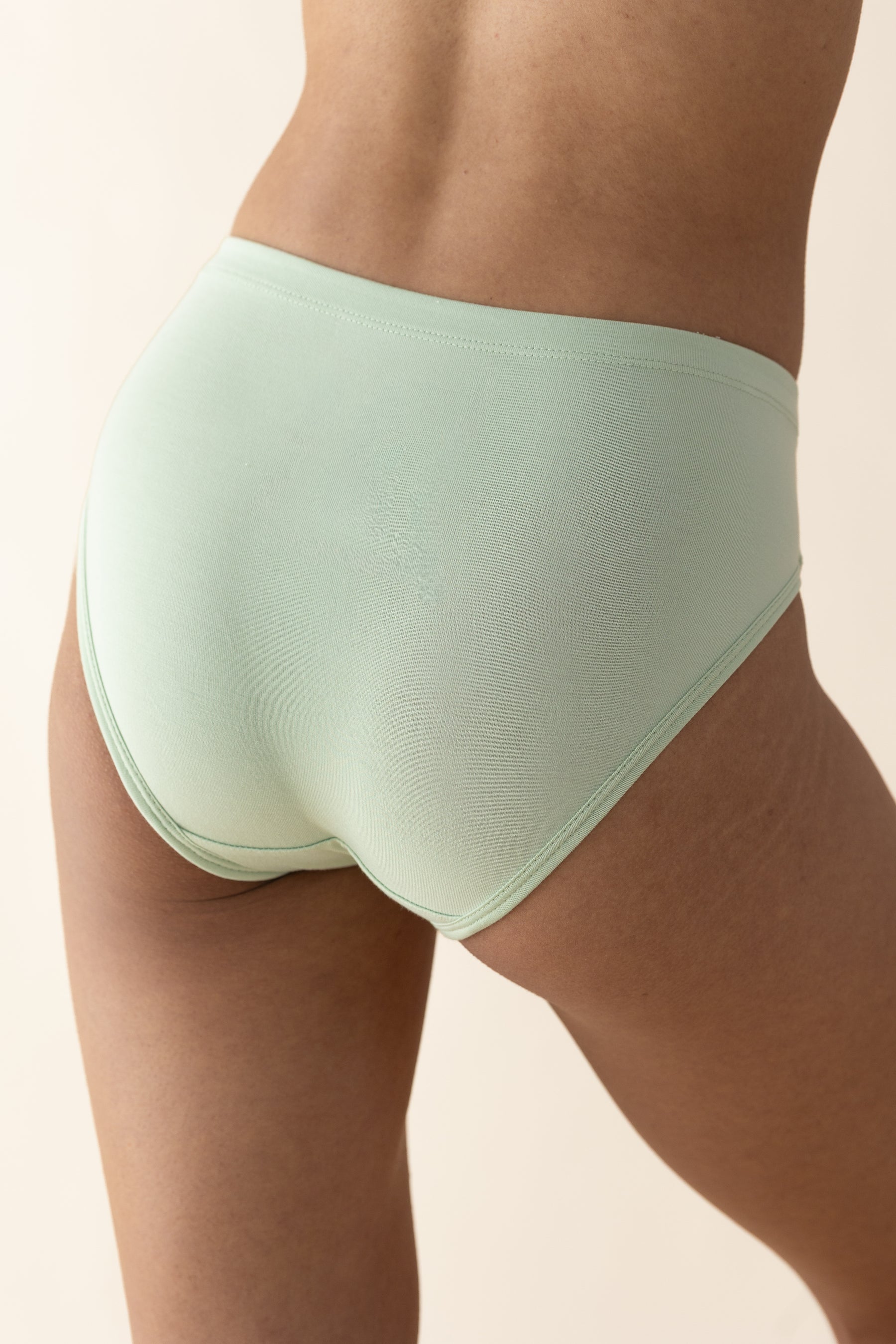 Light green underwear worn by a person on a beige background