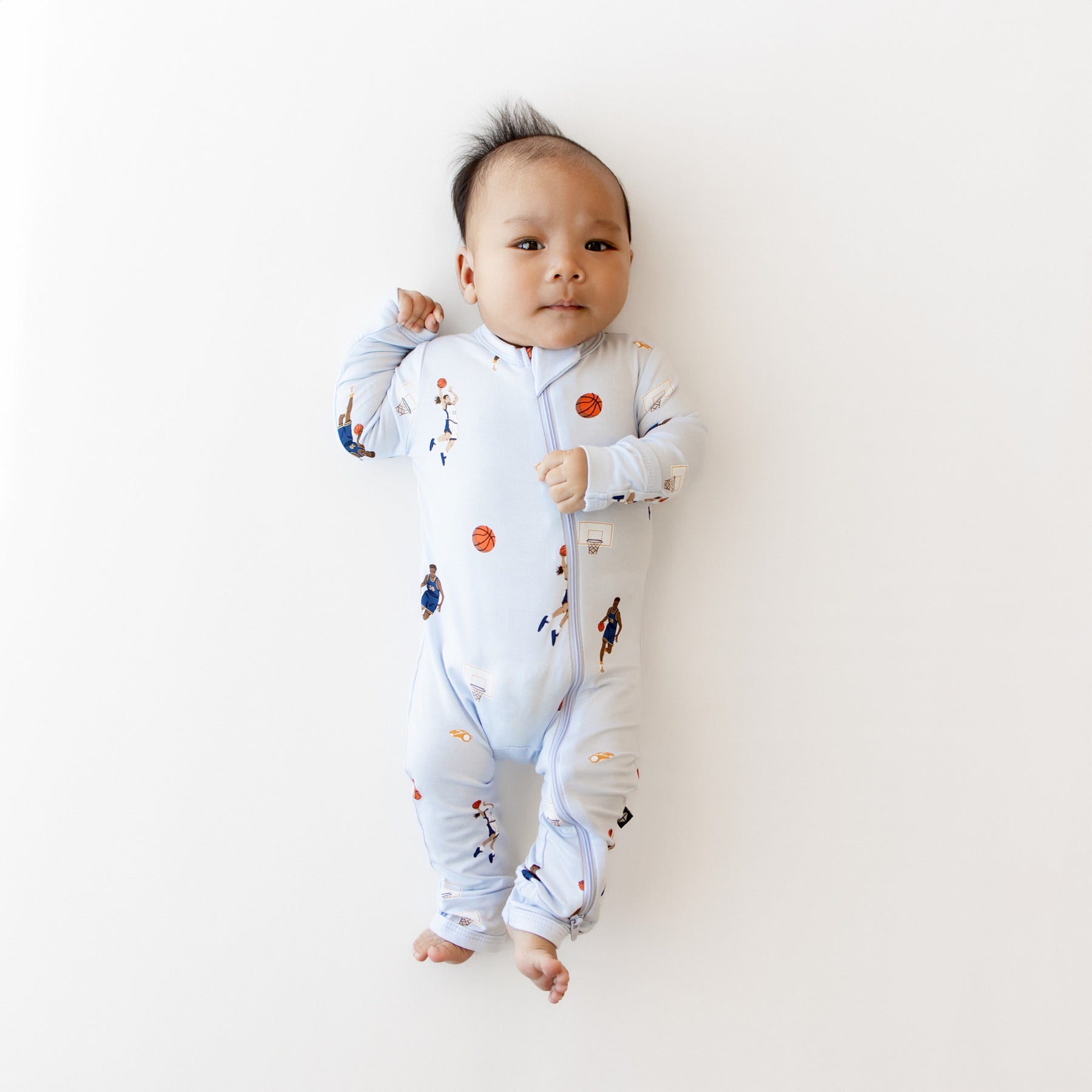 Infant laying down wearing the Zippered Romper in Basketball