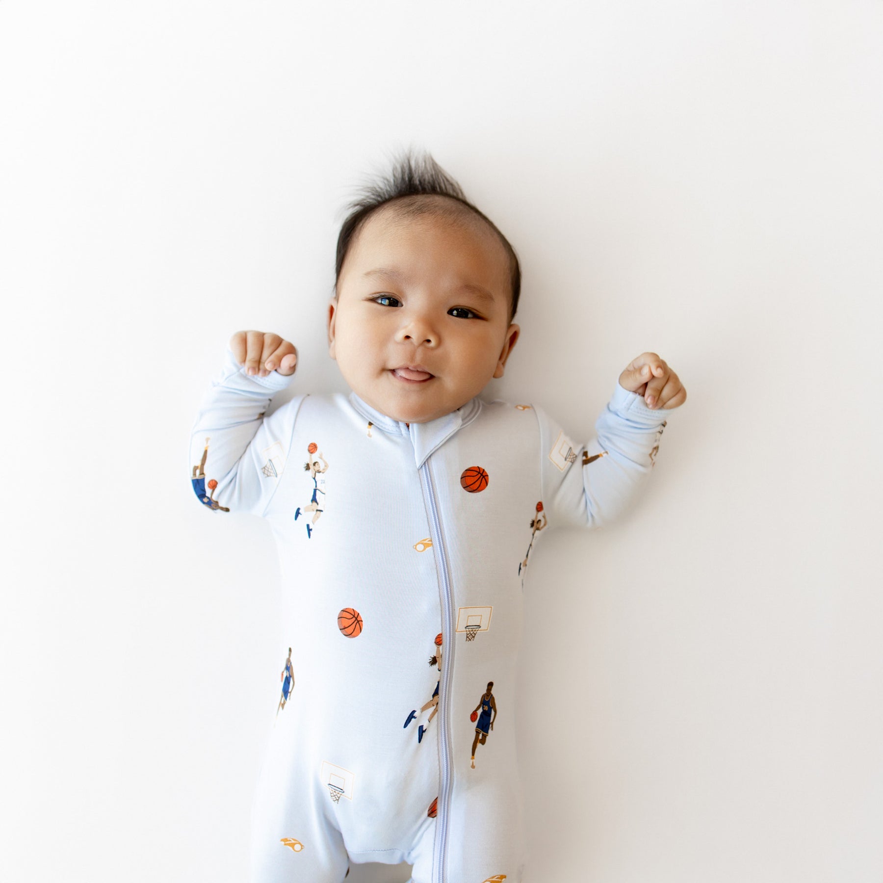Close up of infant sticking out their tongue wearing the Zippered Romper in Basketball